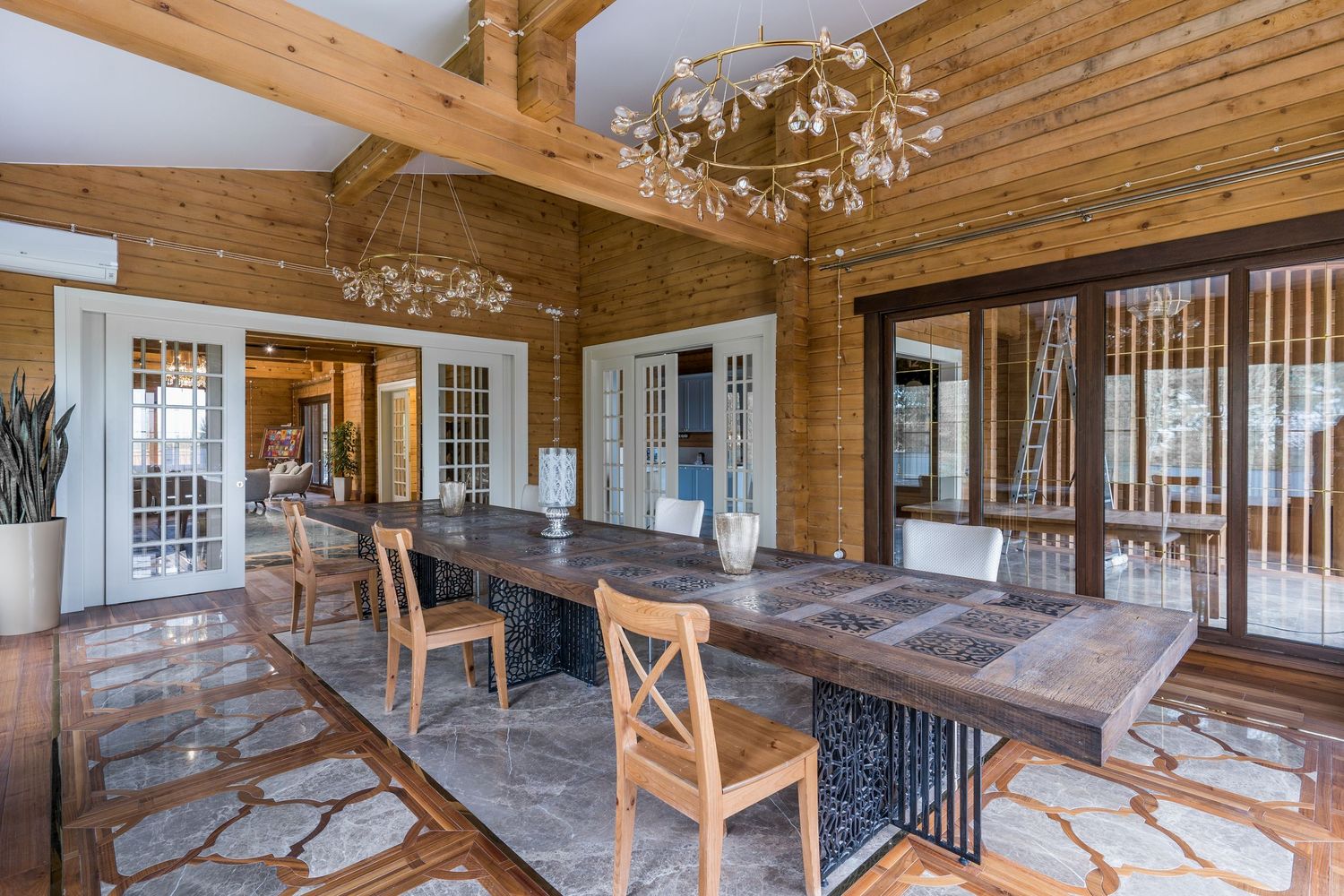 Panoramic view of a lodge-style room with timber ceiling, elegant chandeliers, and wooden furniture.