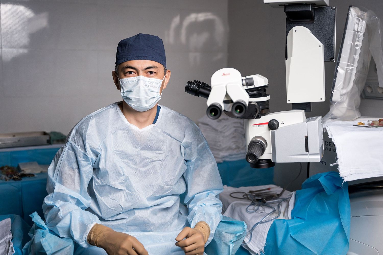 Medical professional in protective gear operating specialized surgical equipment in a clinical setting.