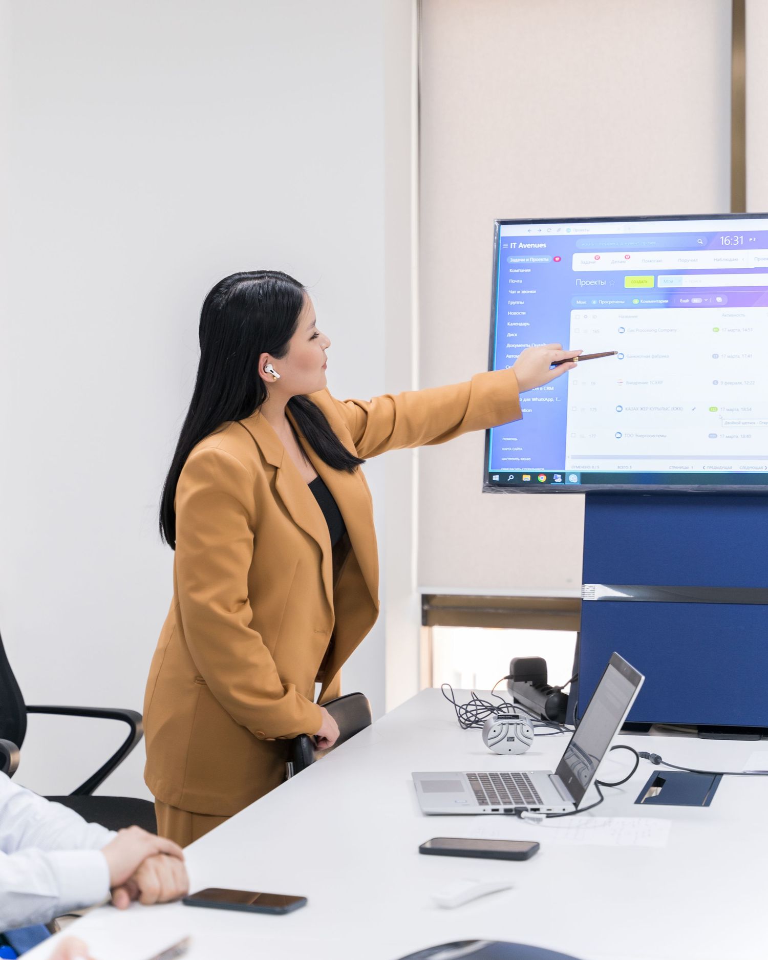 Professional presenting in office meeting room with projected screen display.