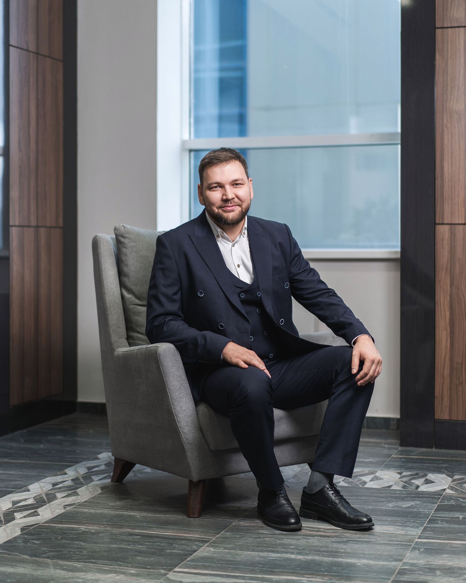 Professional portrait session in modern office space with grey upholstered seating.