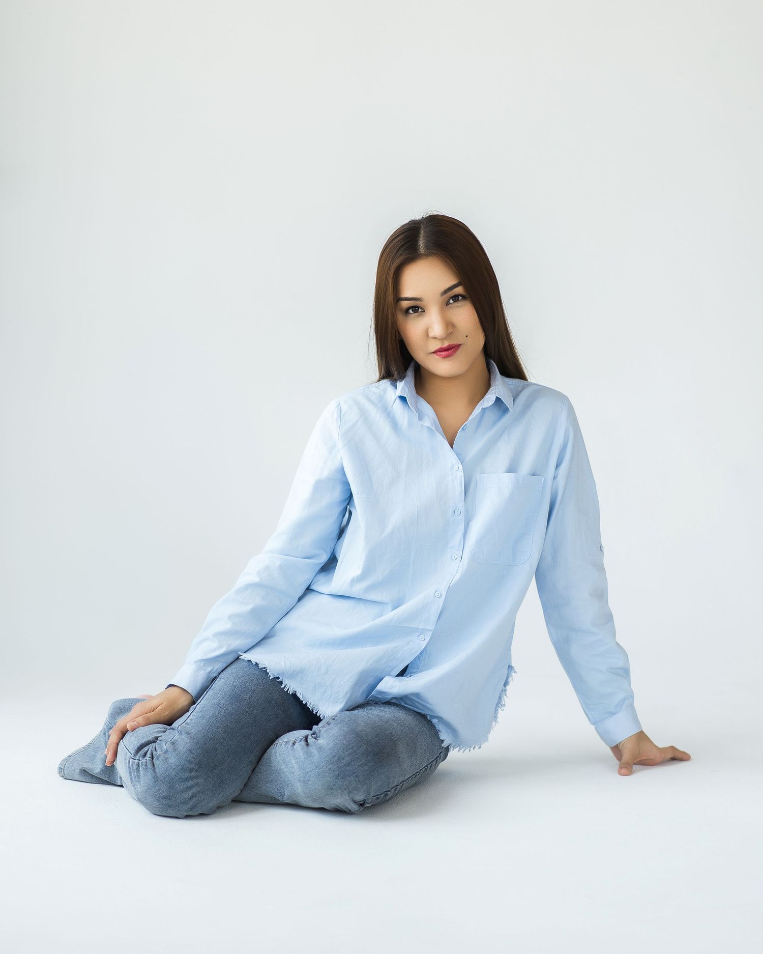 Casual style portrait with light blue button-down shirt and jeans on white background.