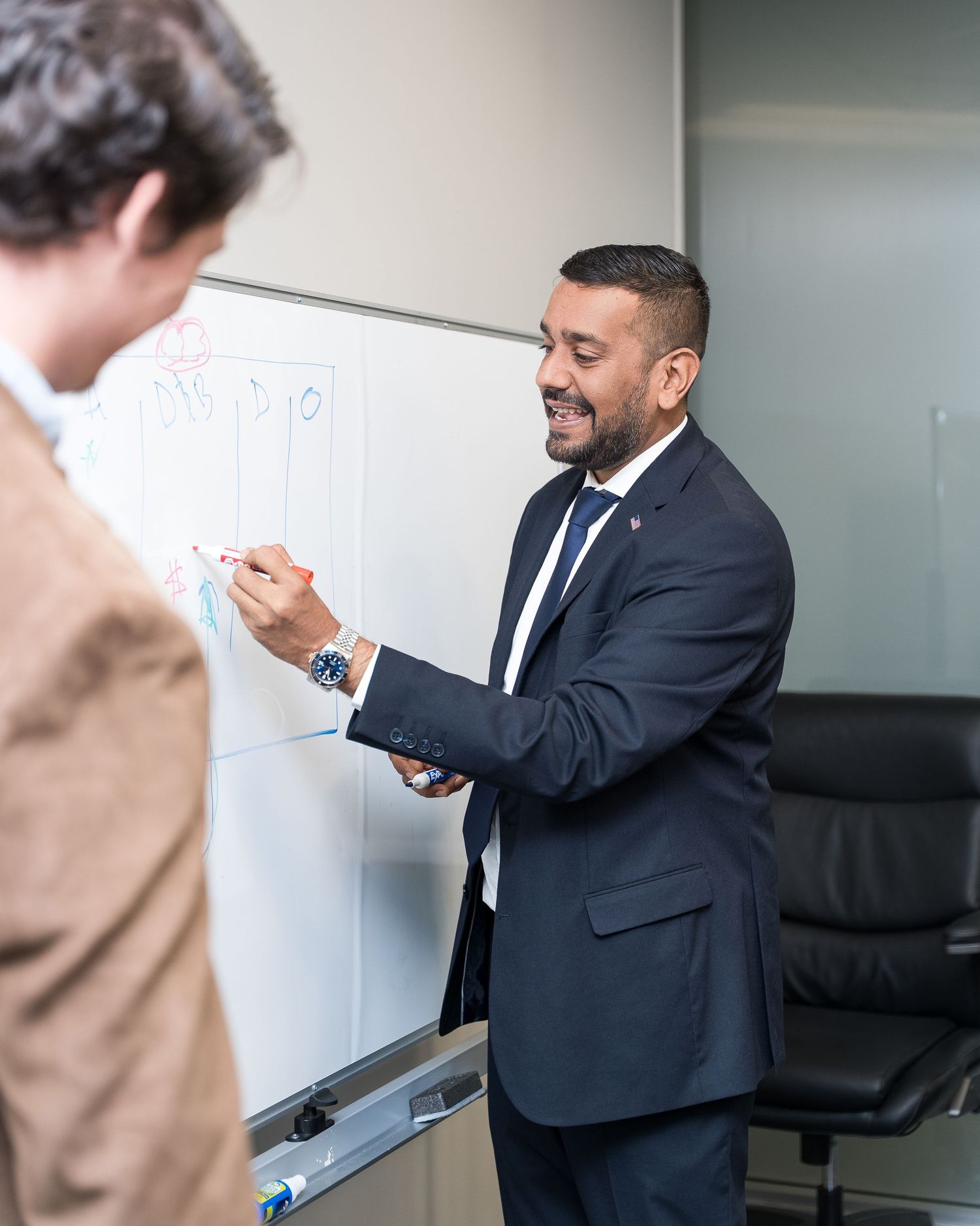 Business professional writing on whiteboard during corporate presentation.