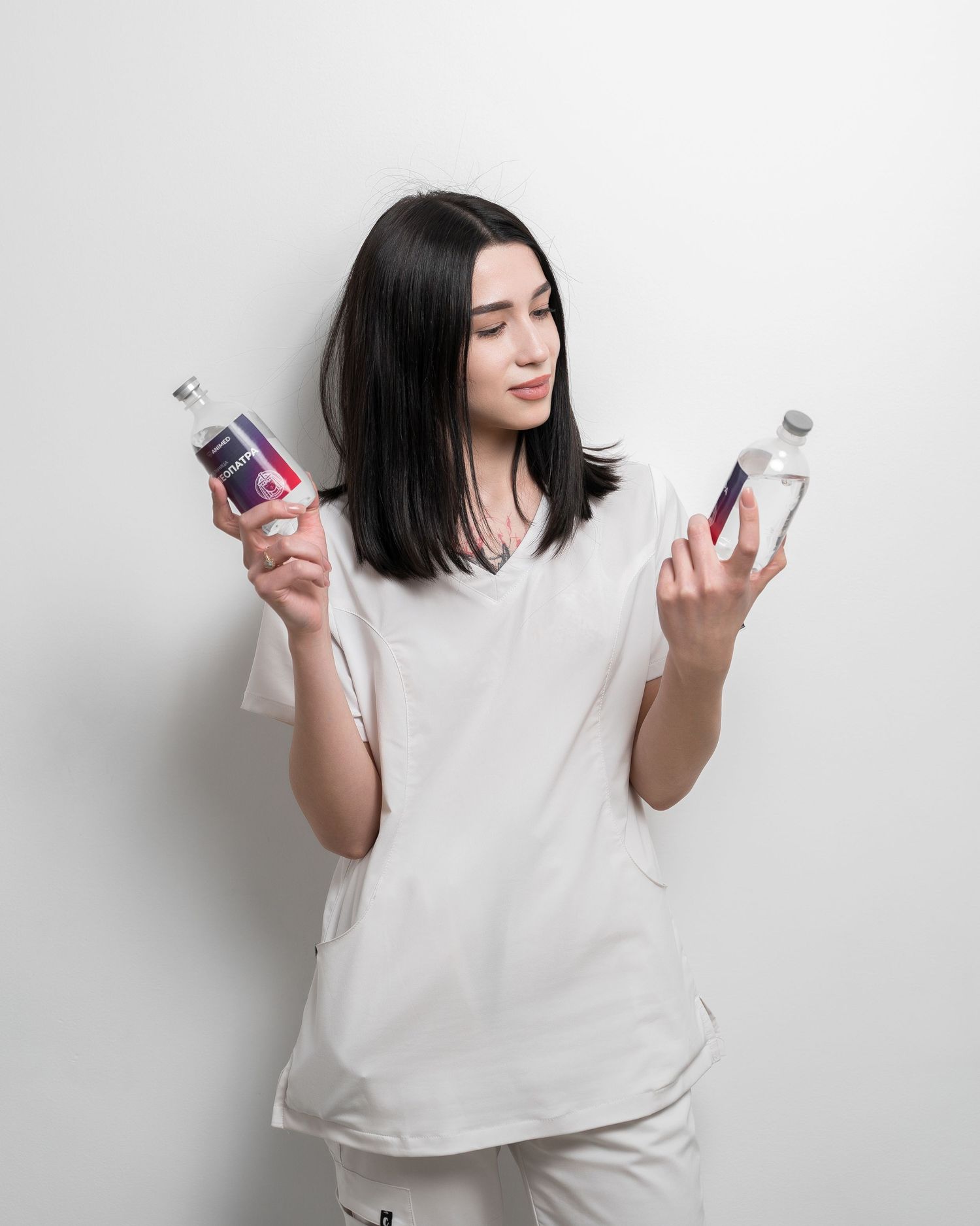 Medical staff member in white uniform holding medical supplies against white background.