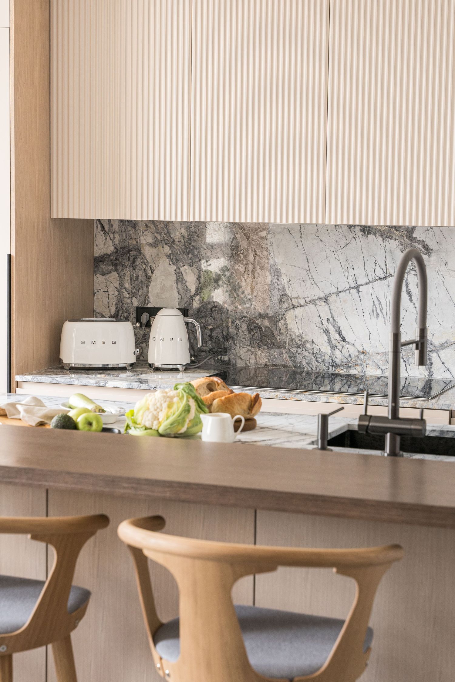 Sleek kitchen design with marble backsplash, wooden dining table and ribbed wall paneling.