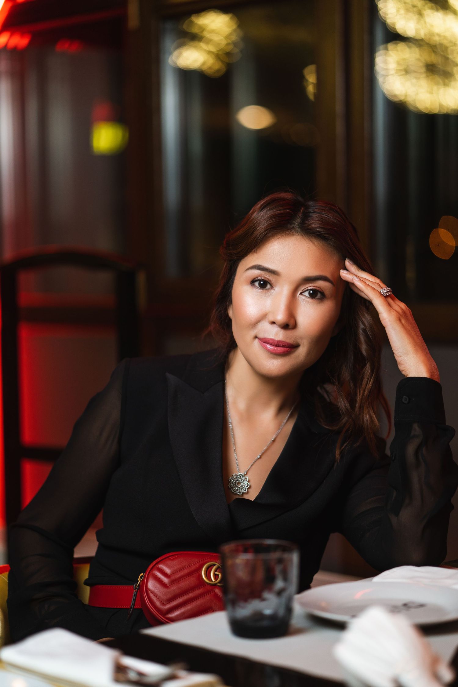 Elegant evening portrait in black attire at upscale restaurant setting.