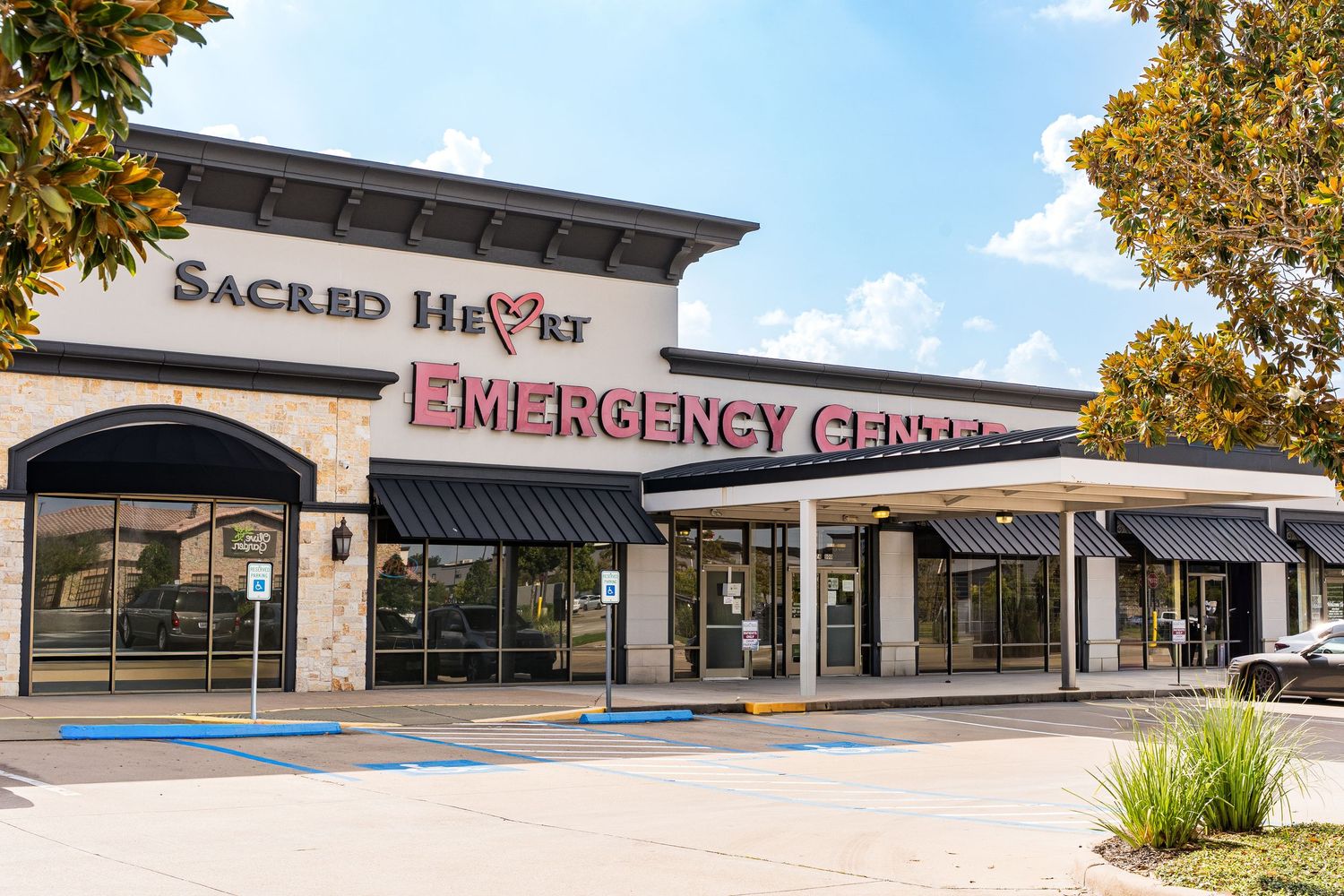 Exterior view of Sacred Heart Emergency Center building with signage and landscaping.