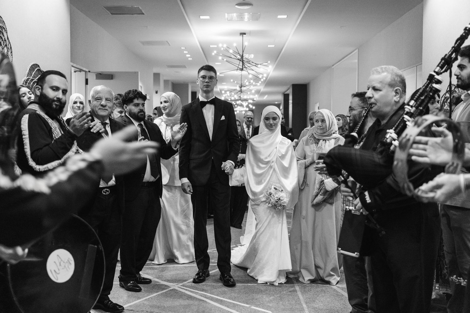 Black and white photo of a bride and groom walking down the aisle at a Muslim wedding ceremony.