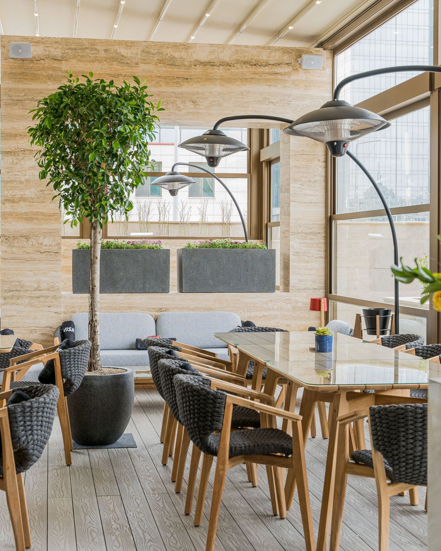 Modern restaurant interior with black woven chairs and wooden tables under pendant lighting.