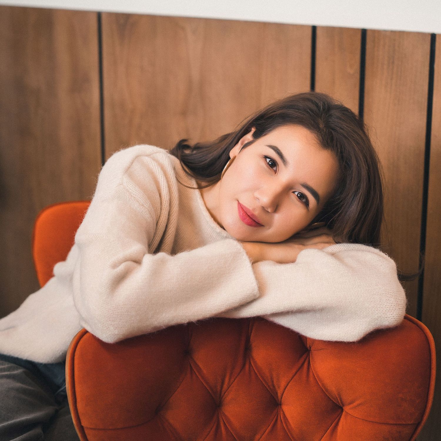 Person lounging on brown tufted couch in casual setting.
