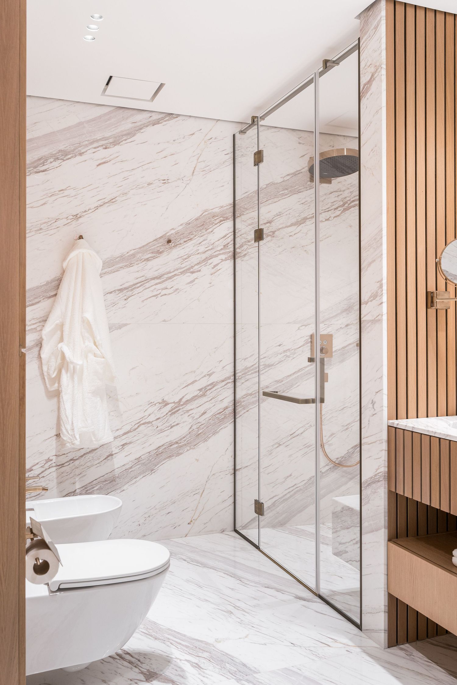 Contemporary bathroom interior with glass partitions, marble walls, and wooden slat details.