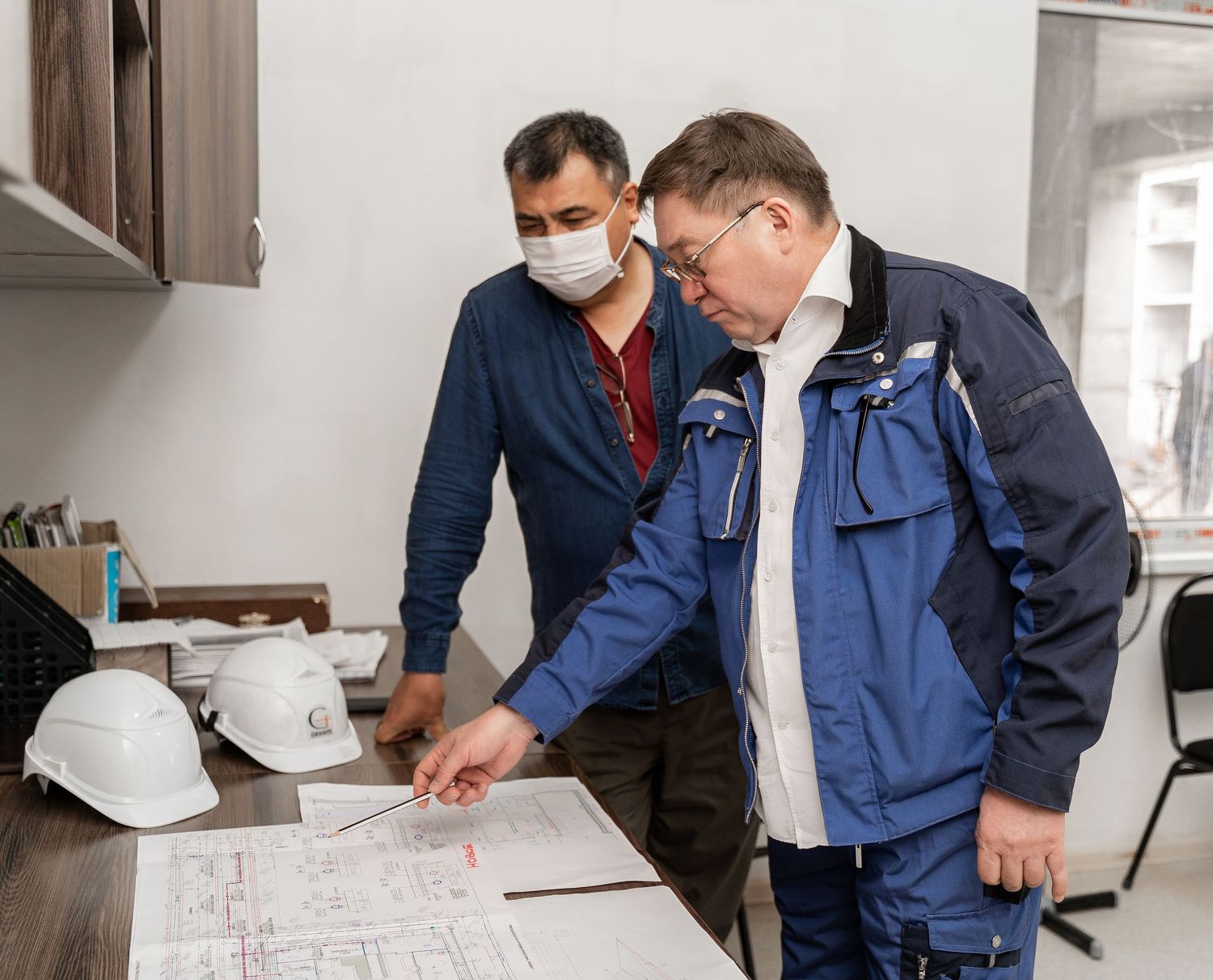 Construction team reviewing architectural drawings and blueprints in an office setting.