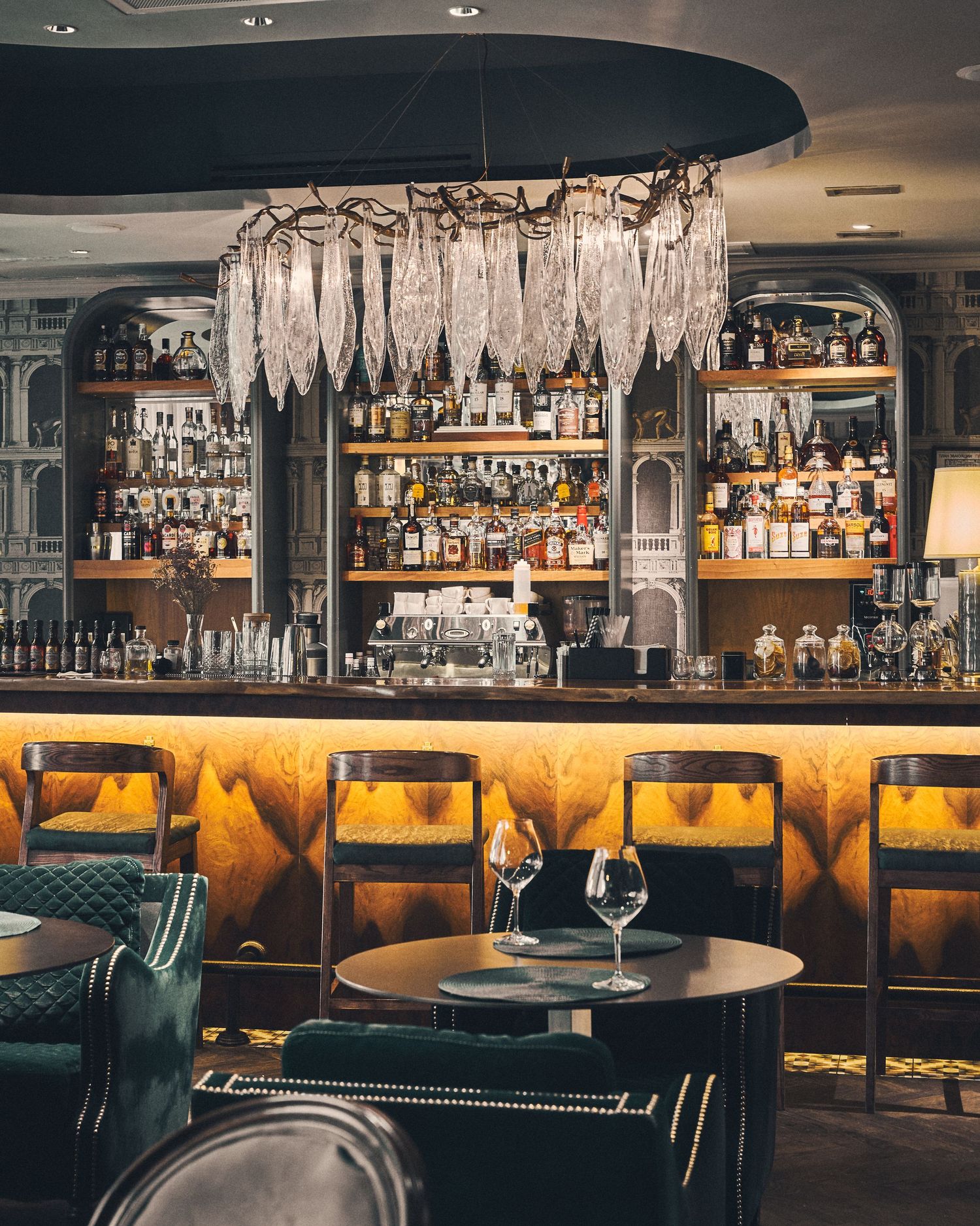 Elegant bar interior with crystal pendant lights and backlit bottle display.