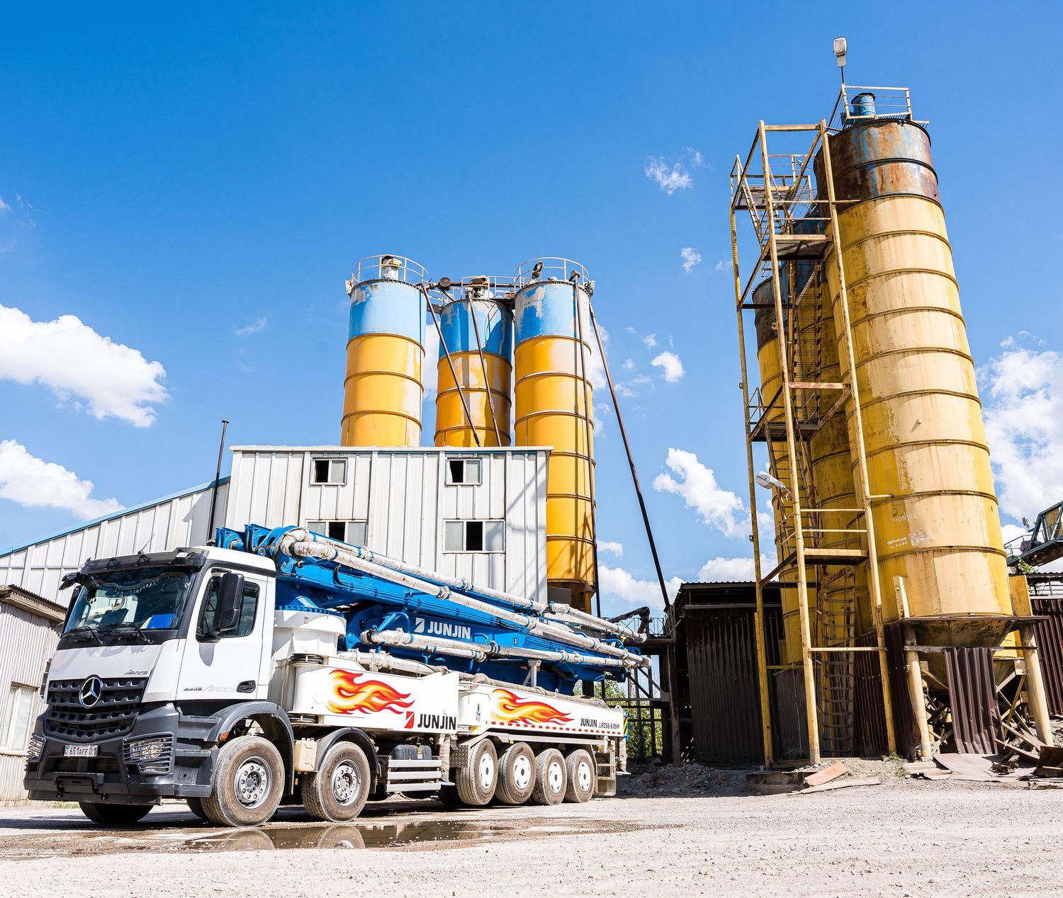 Yellow cement silos and concrete mixing trucks lined up at an industrial facility.