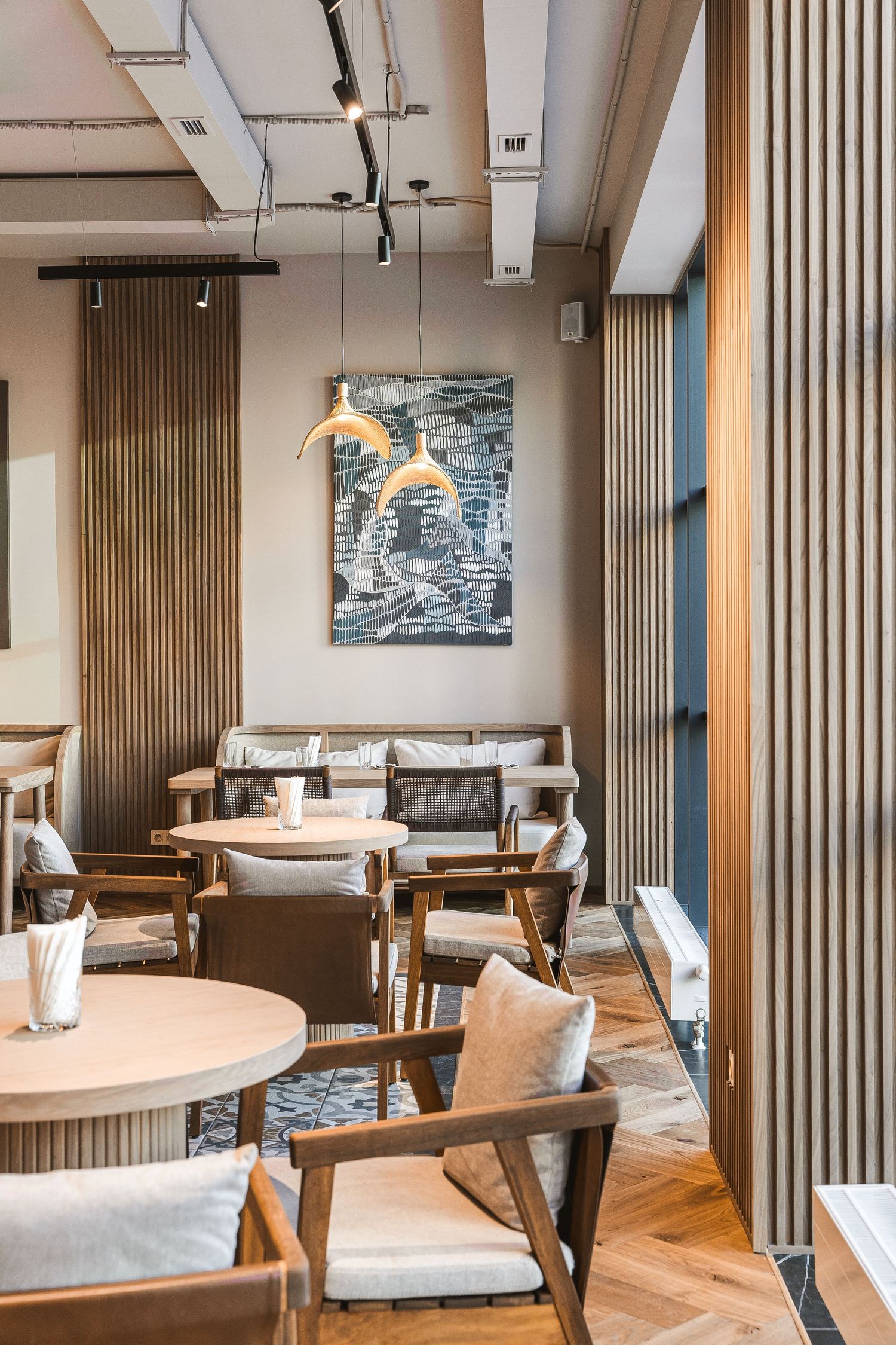 Modern restaurant interior with wooden slat walls and comfortable dining furniture.