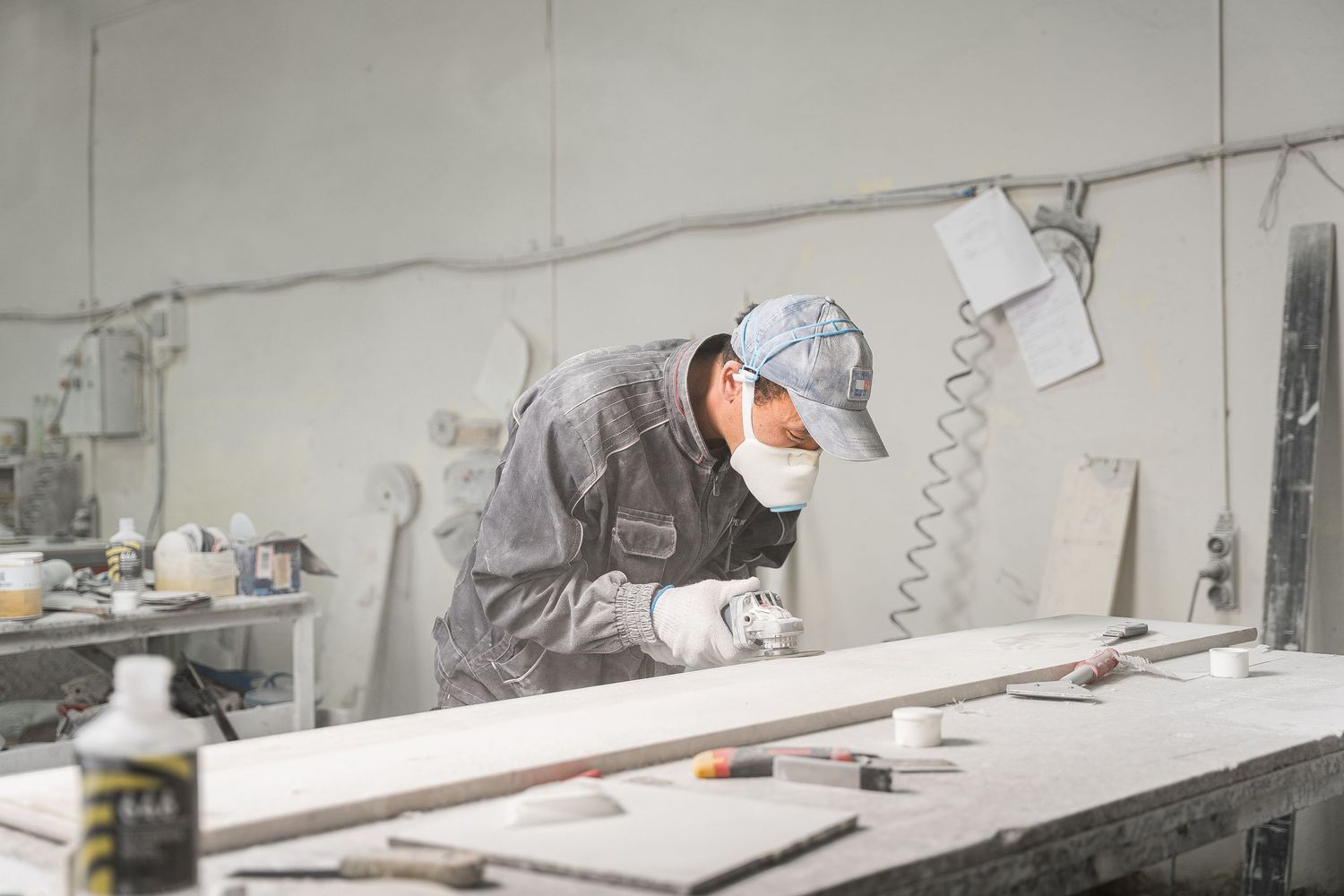 Craftsman carefully working on detailed stone carving designs in a workshop setting.