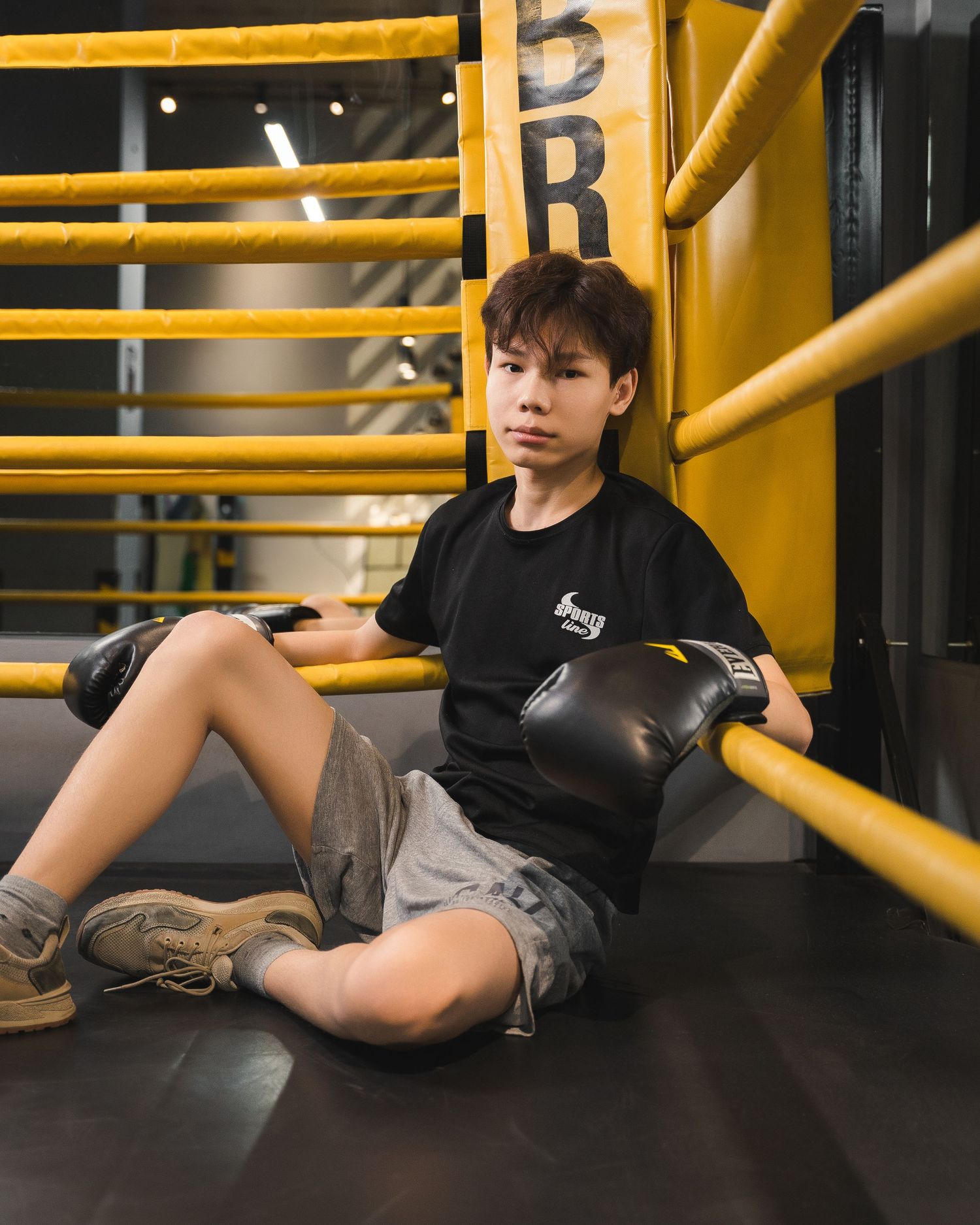 Person in black clothing demonstrating stretching exercises using yellow metal bars at a fitness facility.
