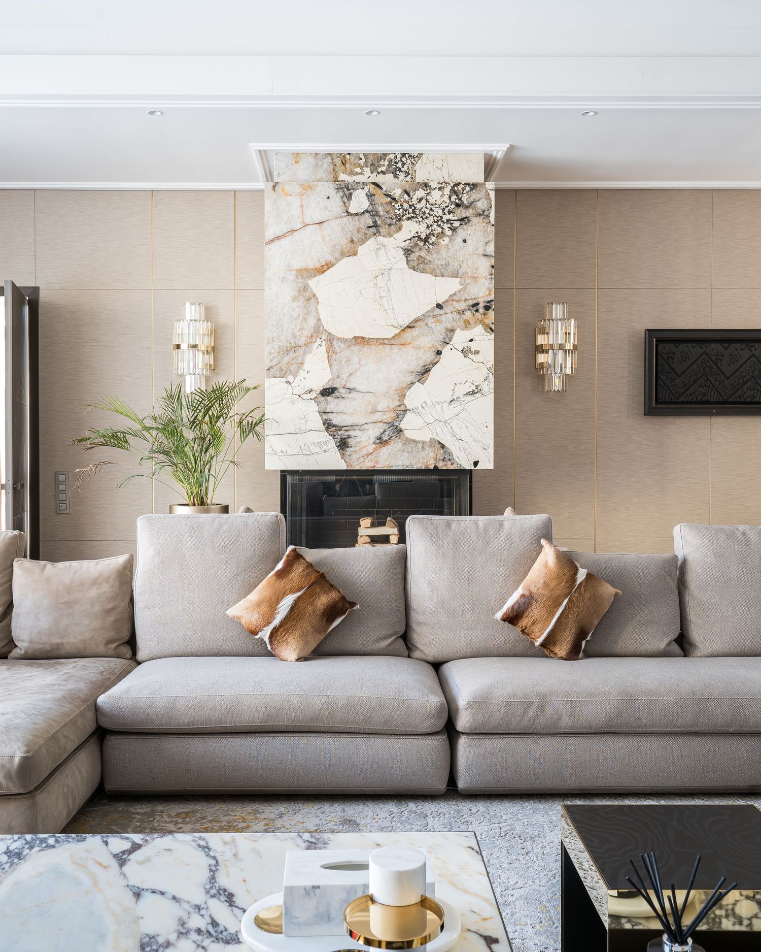 Modern living room with gray sectional sofa, marble accent wall, and decorative lighting fixtures.