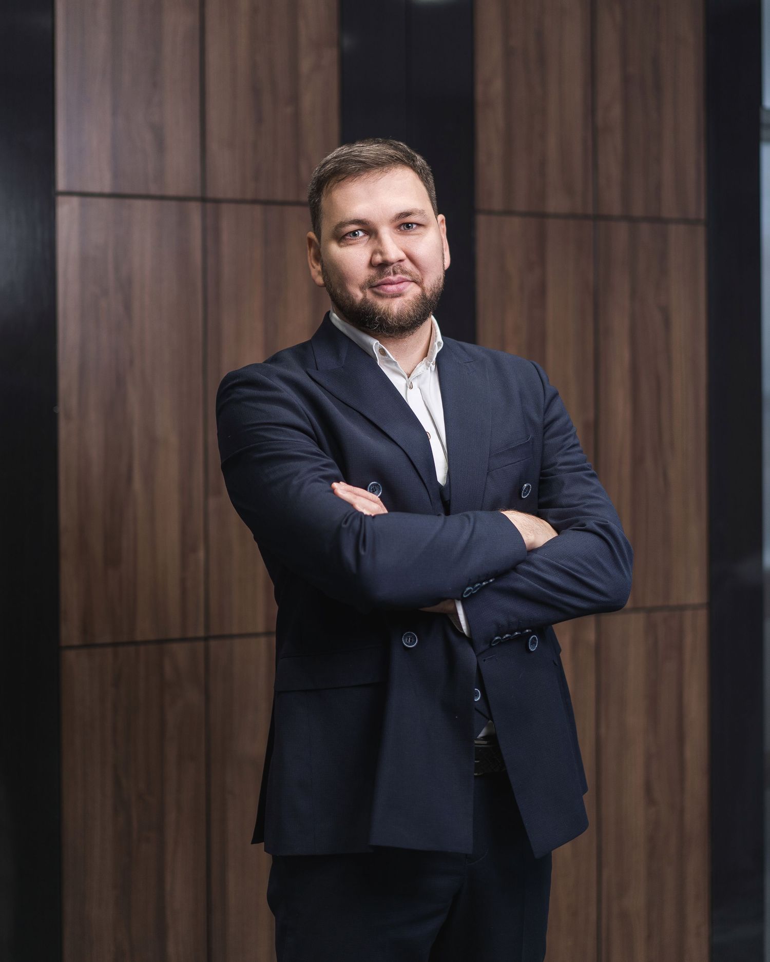 Corporate headshot against wood paneled wall in modern office environment.