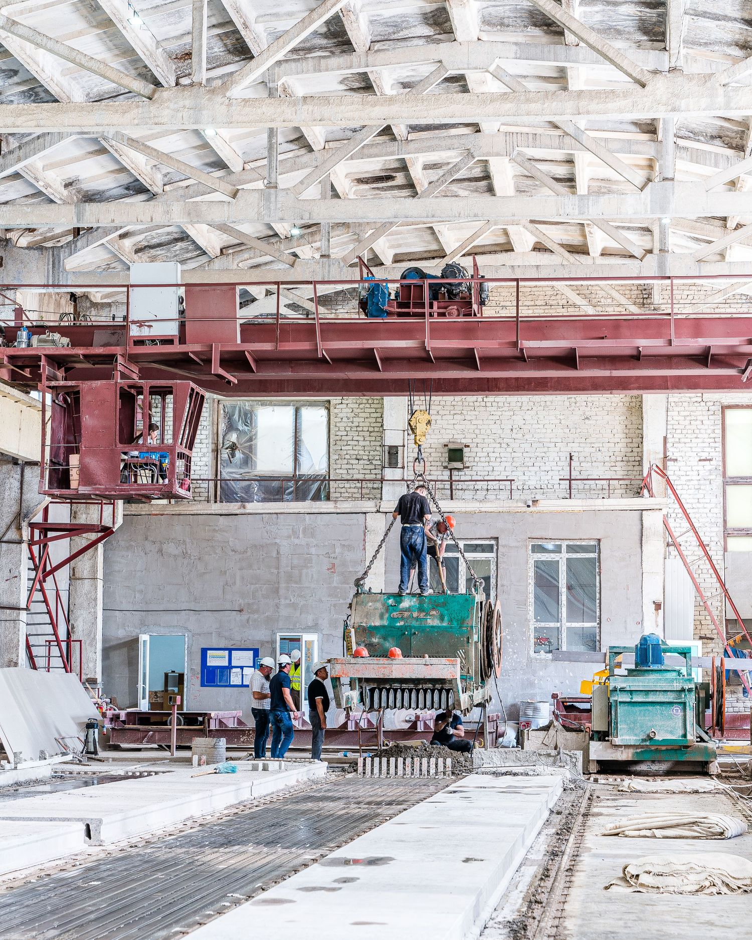 Industrial facility undergoing renovation with workers on elevated platform and construction equipment.