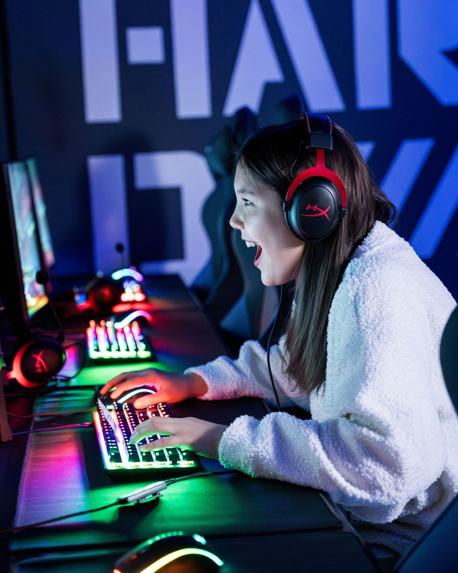 Gamer wearing headphones at computer setup with colorful RGB lighting.