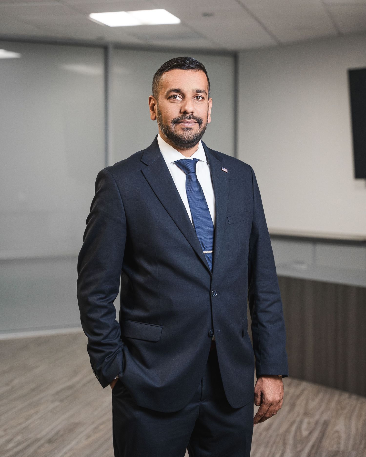Professional business portrait in modern office with grey walls and wood floors.