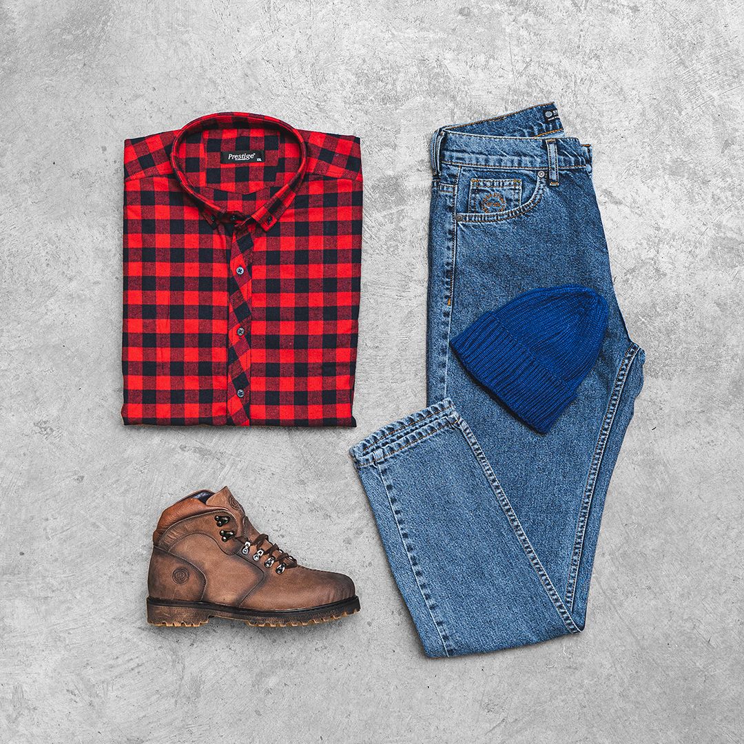 Red plaid flannel shirt paired with blue jeans and brown work boots on grey background.