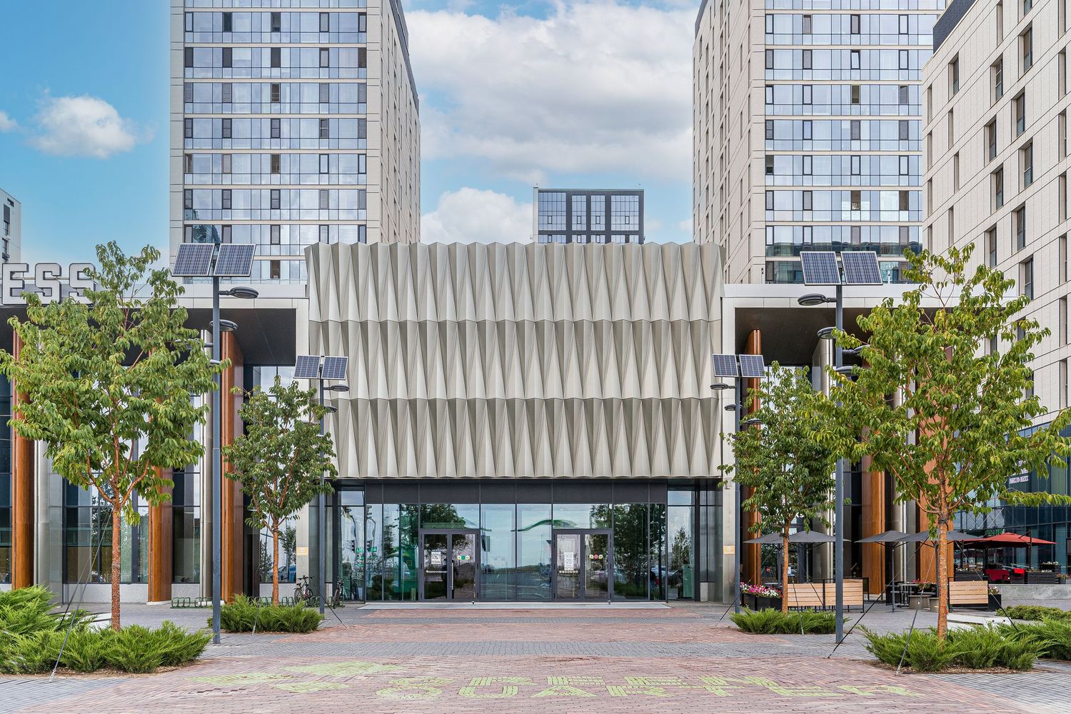 Modern urban apartment complex exterior with landscaped courtyard and glass facades.