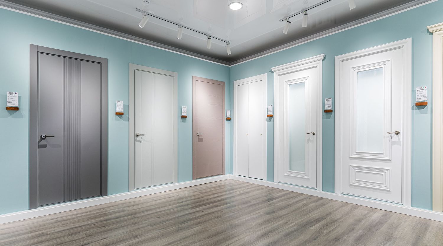 Long hallway with mint green walls, white trim, and gray doors in modern office building.