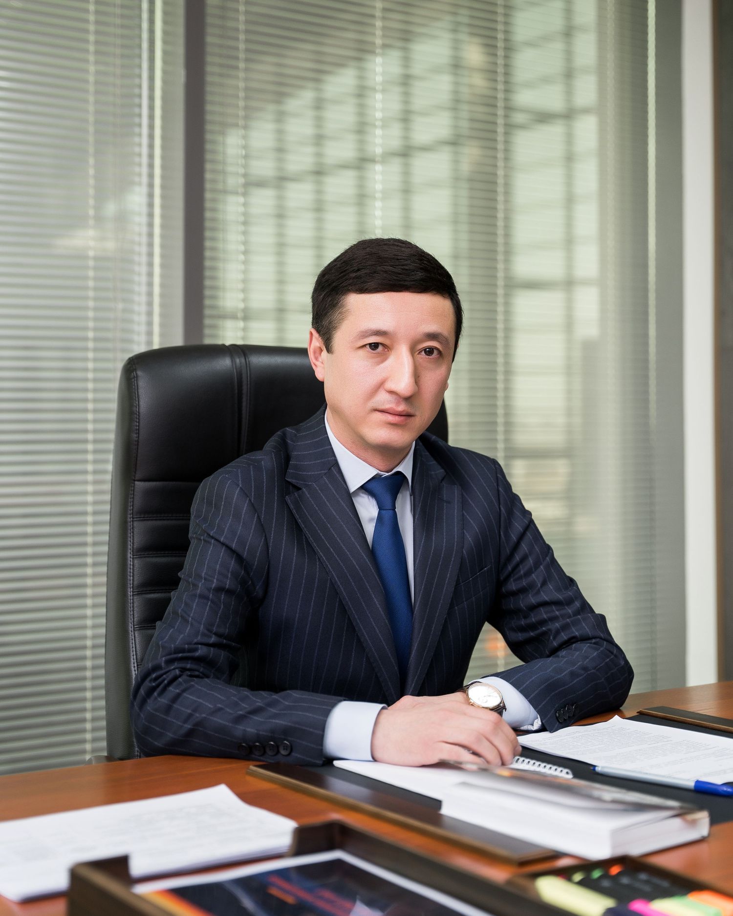 Business executive in pinstripe suit works at desk reviewing papers in corporate office.