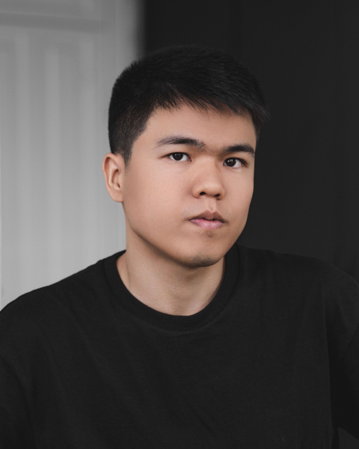 Professional headshot of person wearing black sweater against light background.