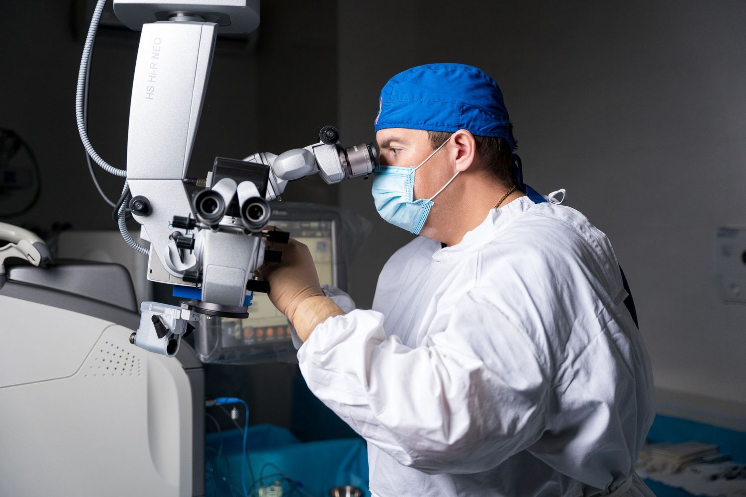 Healthcare professional in surgical attire working with precision medical instruments.