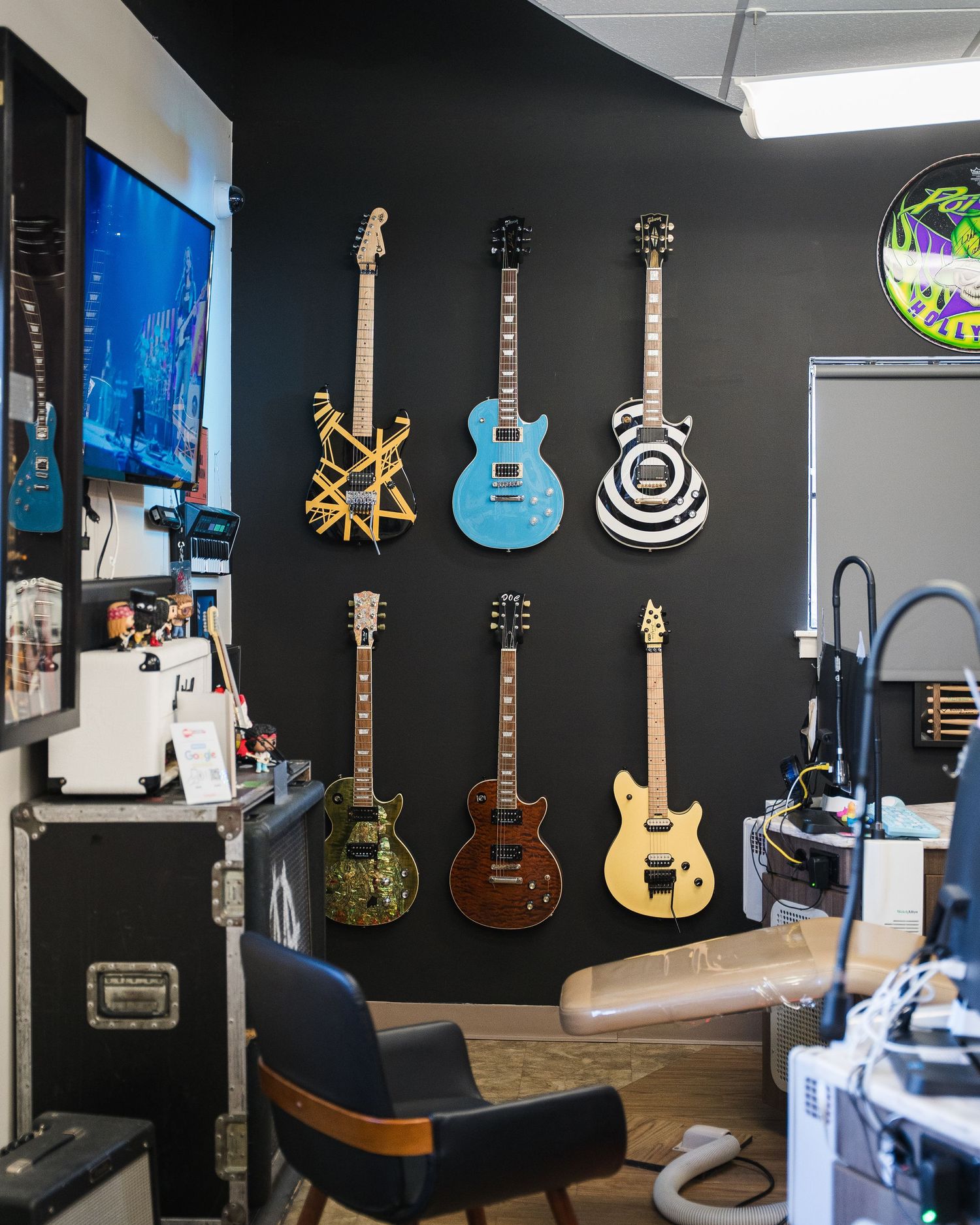 Collection of guitars displayed on black wall in music-themed office space.