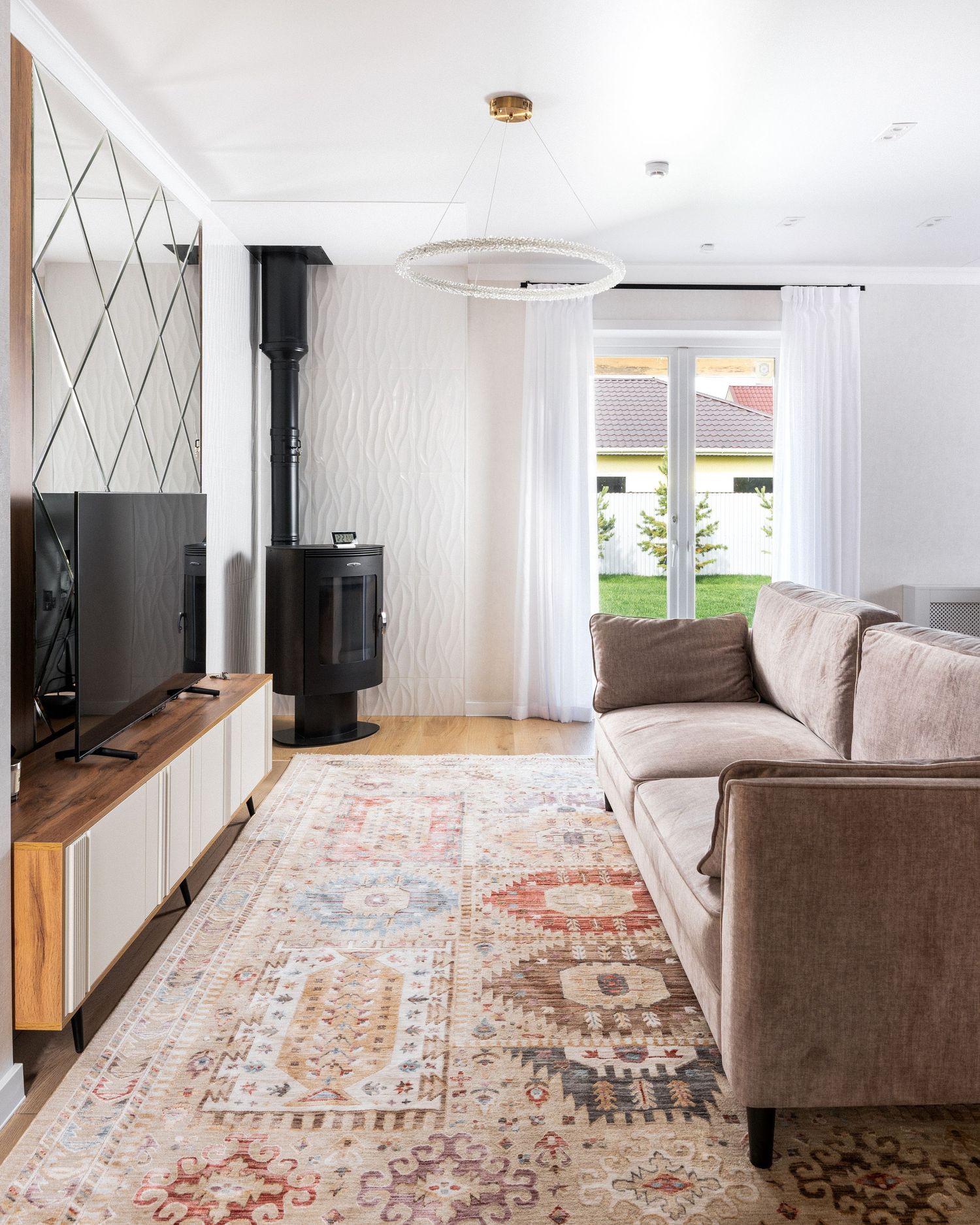 Contemporary living room with brown sofa, patterned area rug, and large windows letting in natural light.