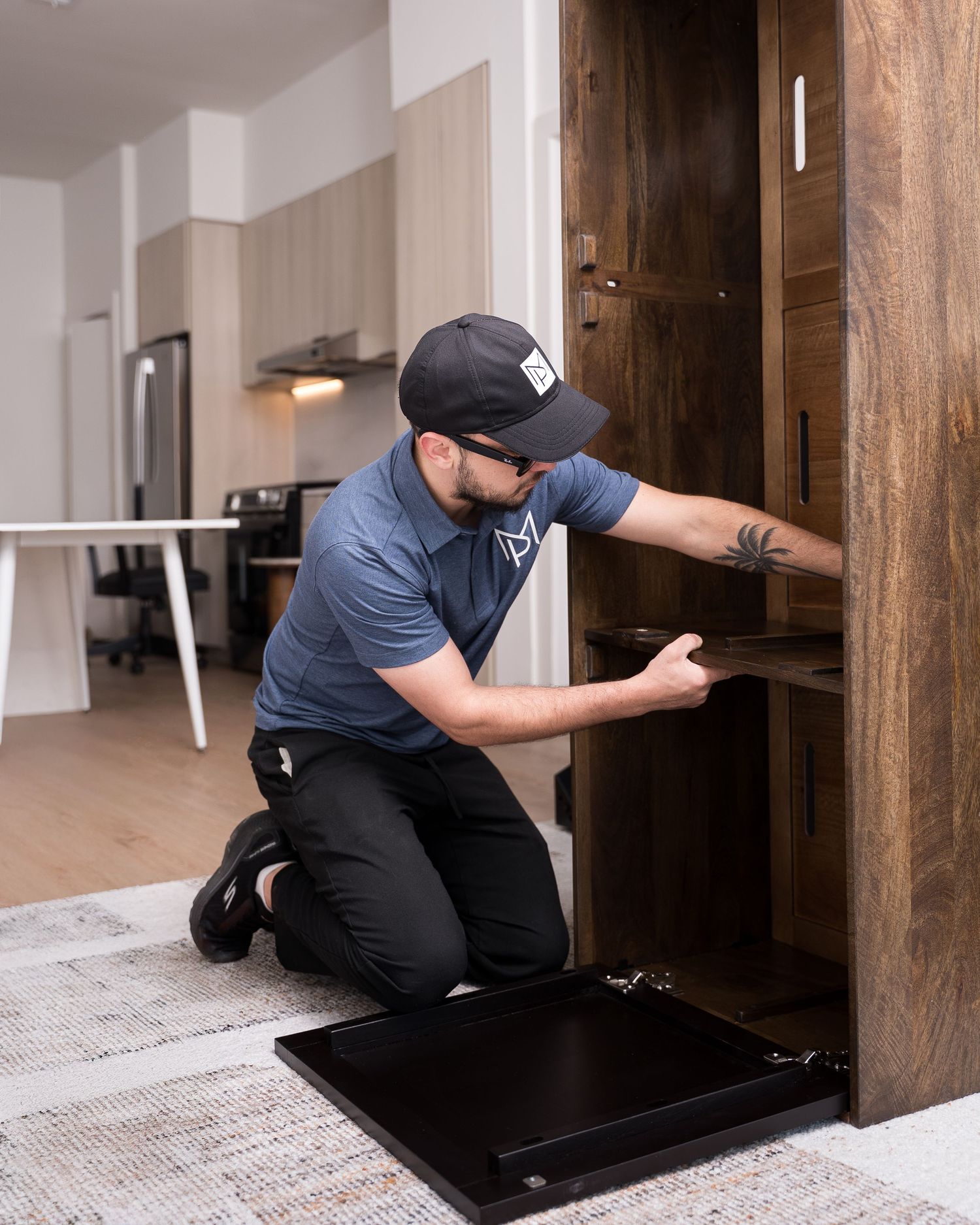 Service worker in uniform performing maintenance check on dark wooden cabinet.