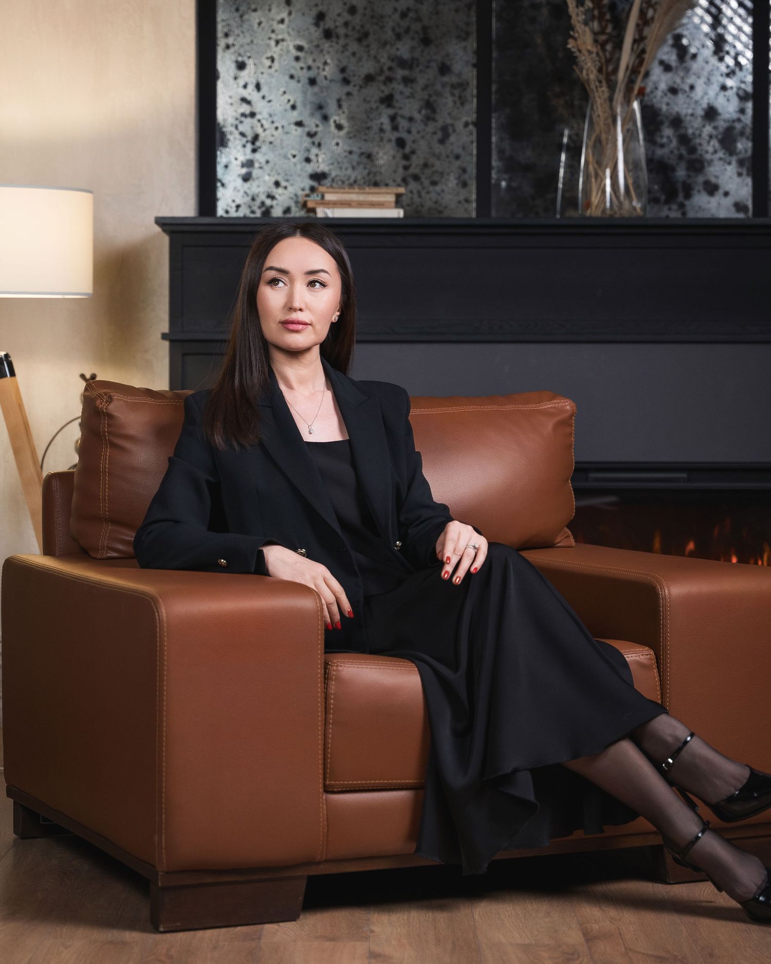 Business professional relaxing on brown leather couch in modern office setting.