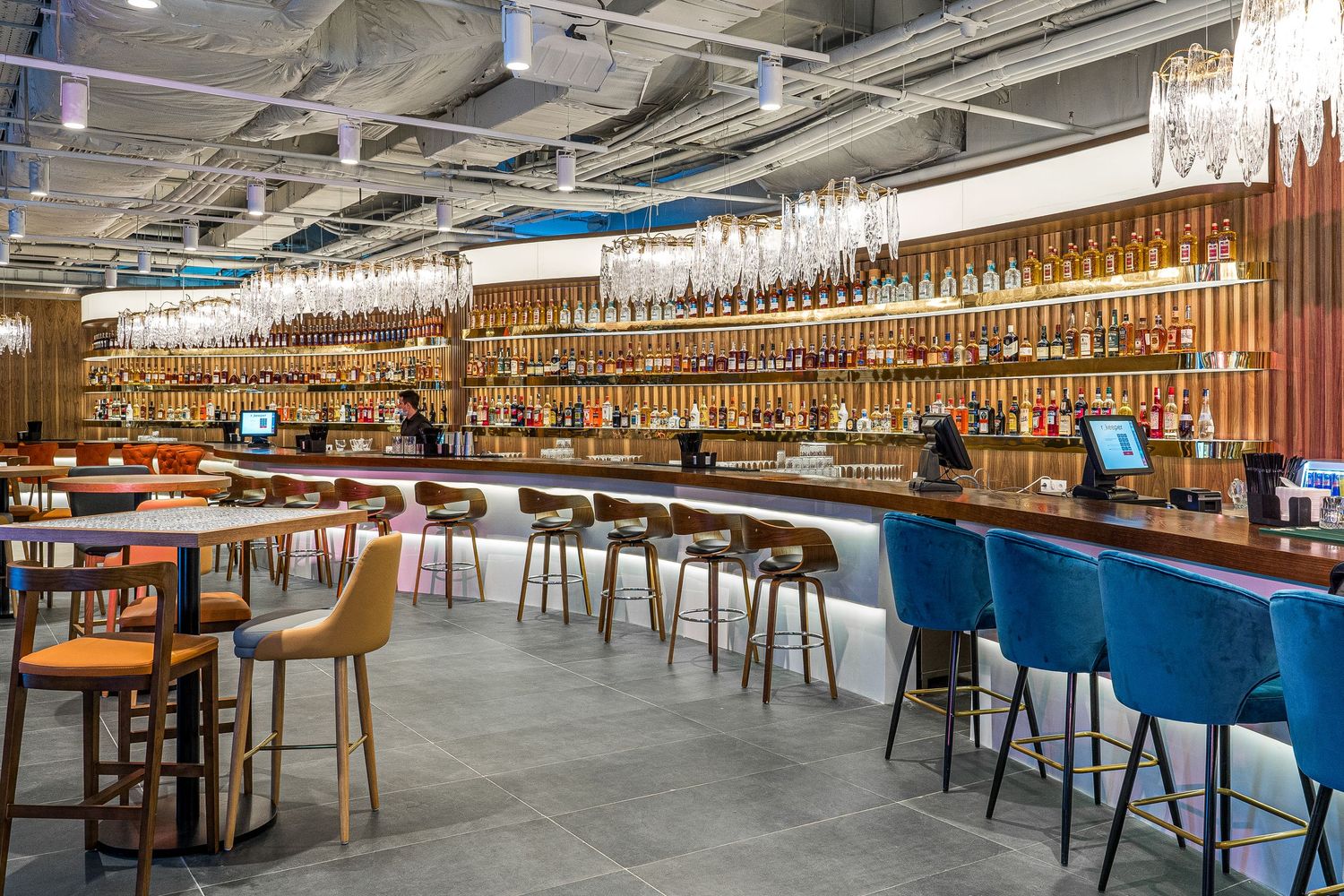 Spacious industrial-style cafeteria with wooden furniture and exposed ceiling infrastructure.