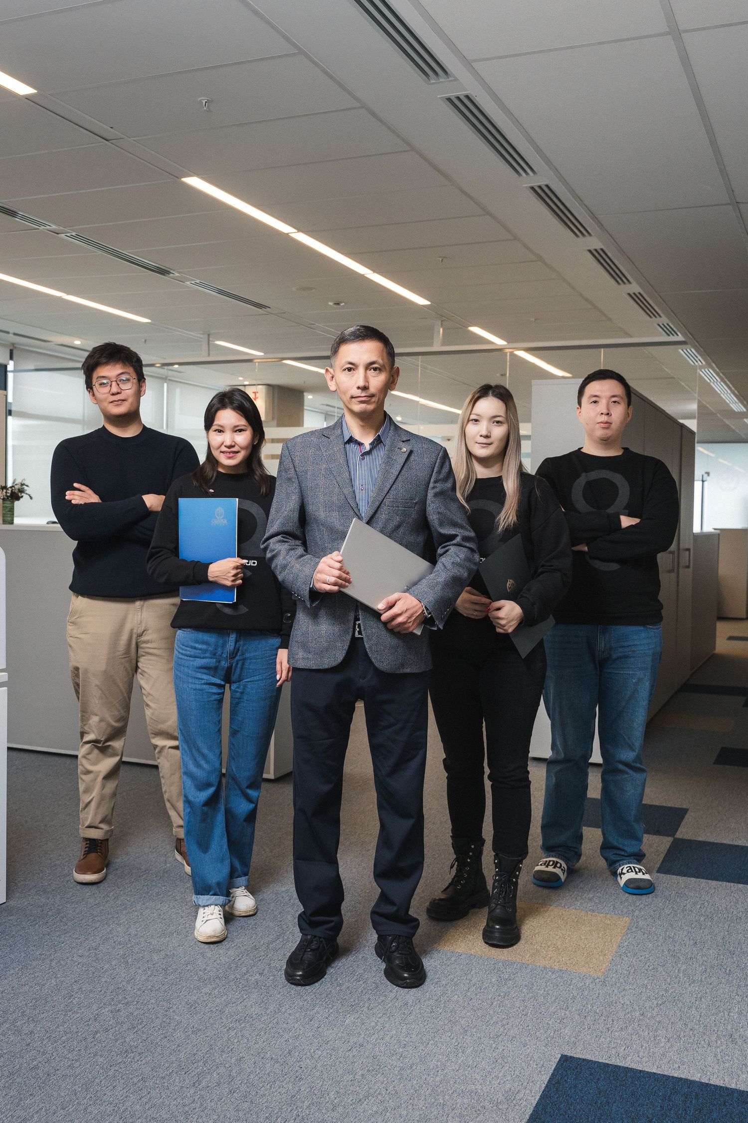 Business team standing together in office holding folders and documents.