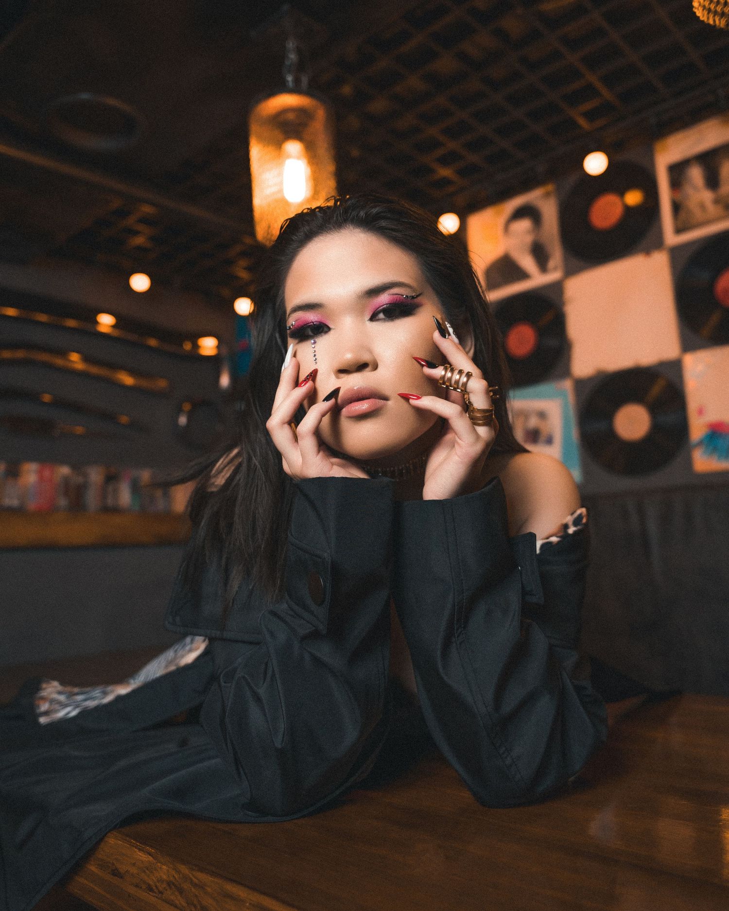 Artistic portrait with dramatic makeup and black clothing in dimly lit venue.
