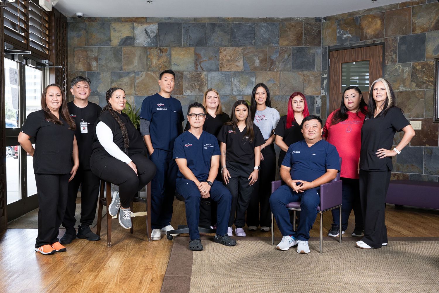 Medical staff members pose together in a modern healthcare facility with stone wall features.