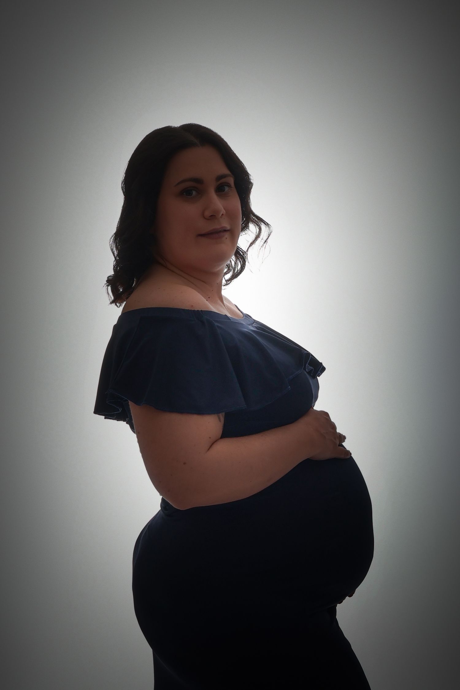 Femme enceinte en rouge assise, séance photo maternité en studio