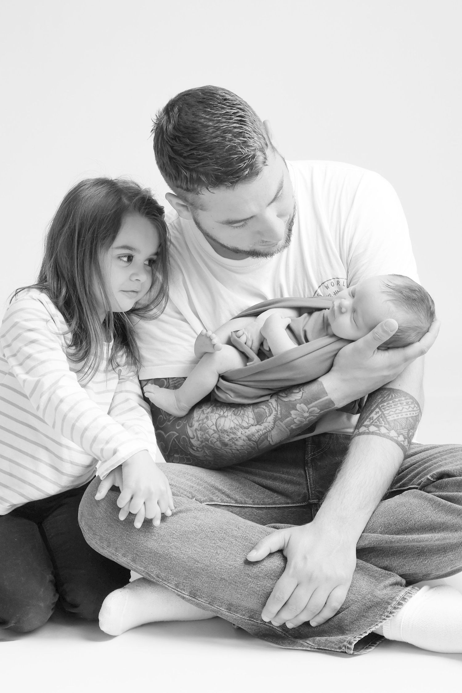 Papa et grande sœur tenant le nouveau-né ensemble, séance famille naissance