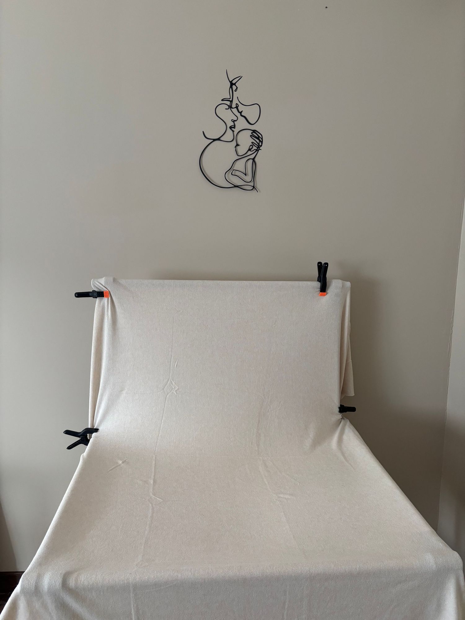 Studio Cindy Poulet Photographe : décor minimaliste pour séance nouveau-né avec fond textile beige et décoration murale mère-enfant.