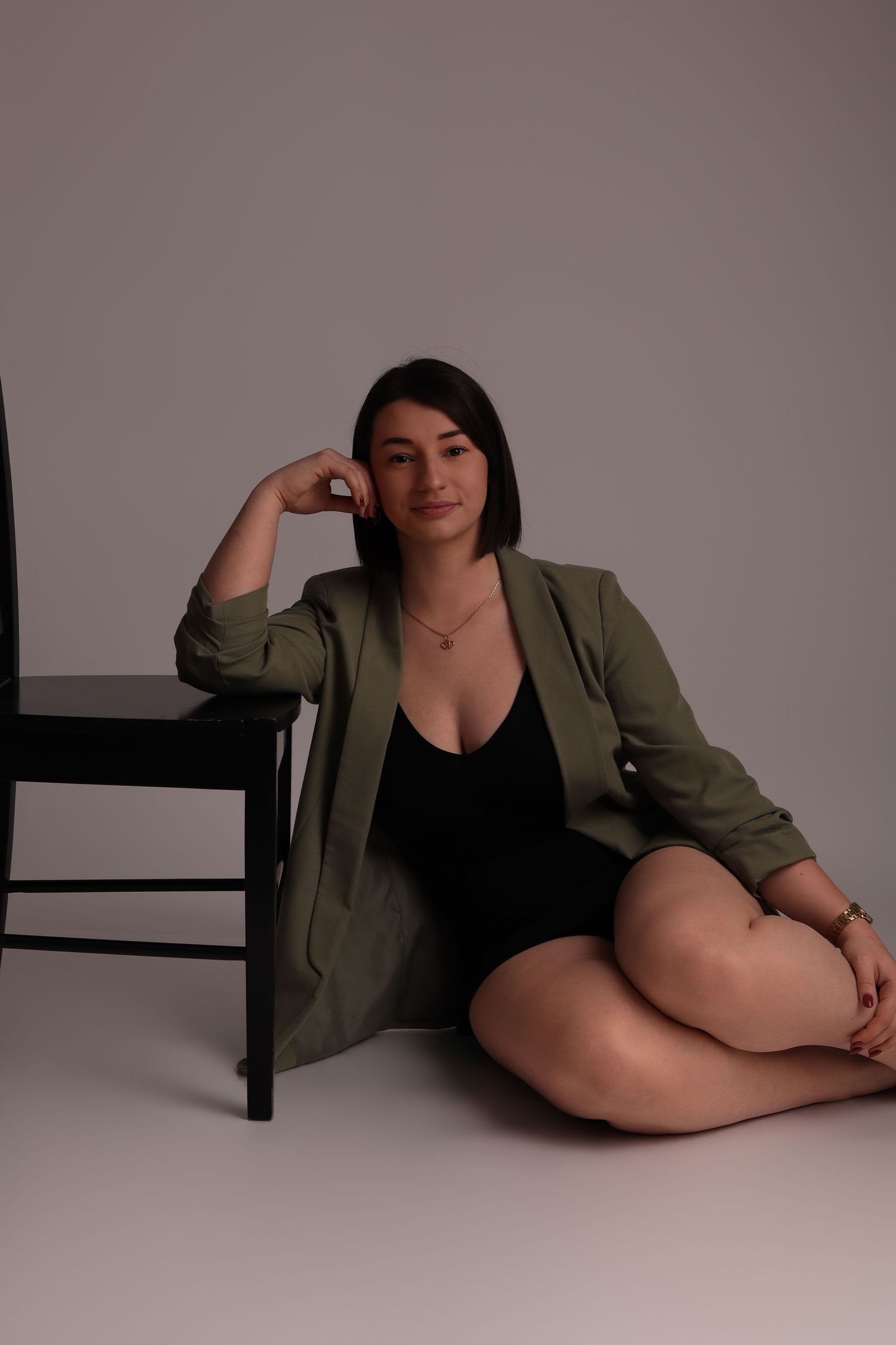 Femme en veste verte assise au sol, portrait en studio