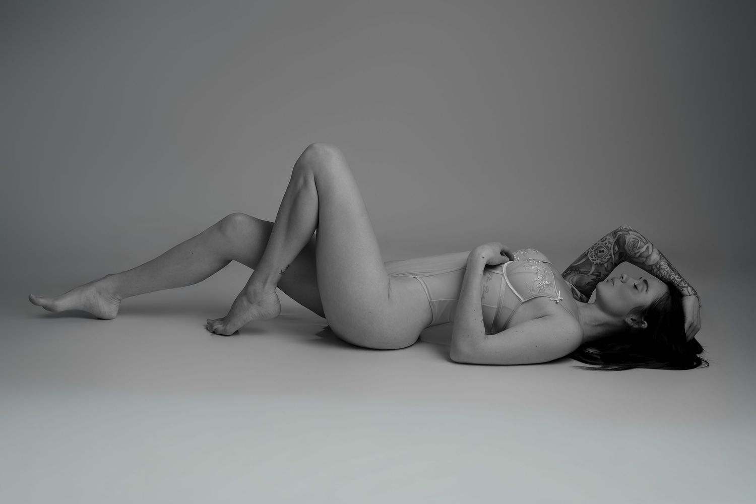 Femme allongée en sous-vêtements blancs sur fond gris, portrait artistique