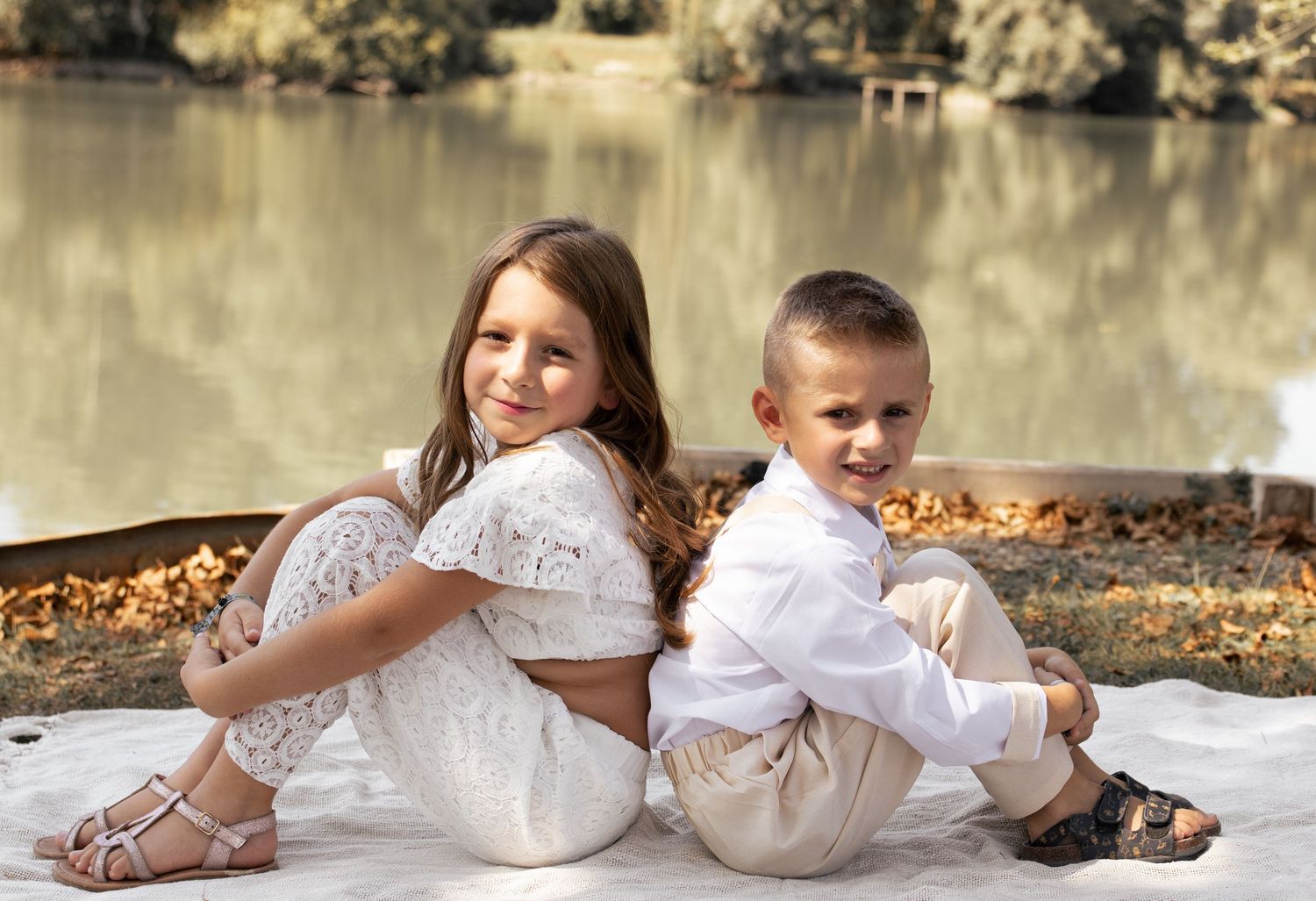 Frère et sœur complices assis dos à dos au bord d'un lac. Séance photo enfants en nature par Cindy Poulet à Septvaux, Aisne.