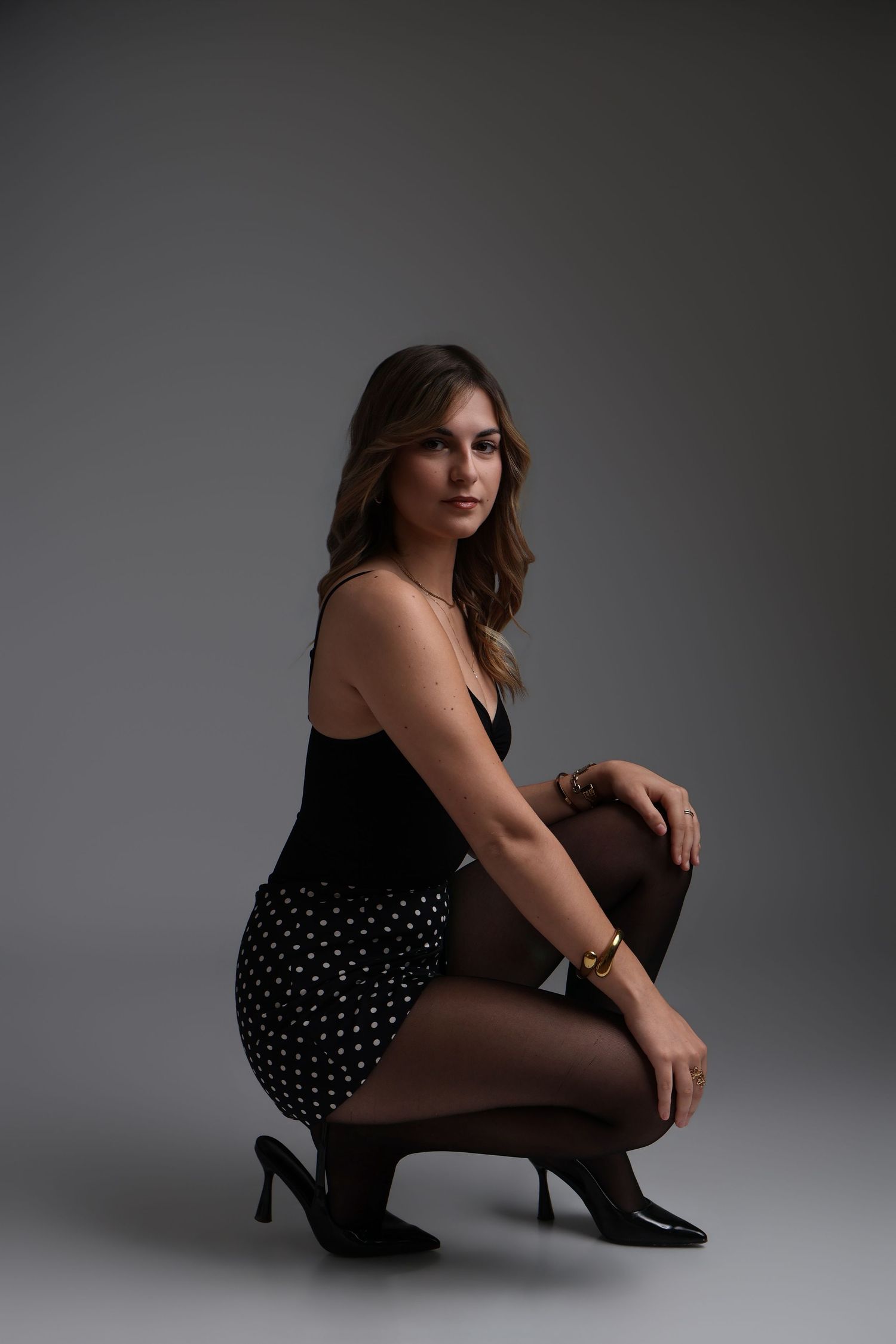 Femme en tenue noire accroupie en talons hauts, séance photo studio - Cindy Poulet photographe