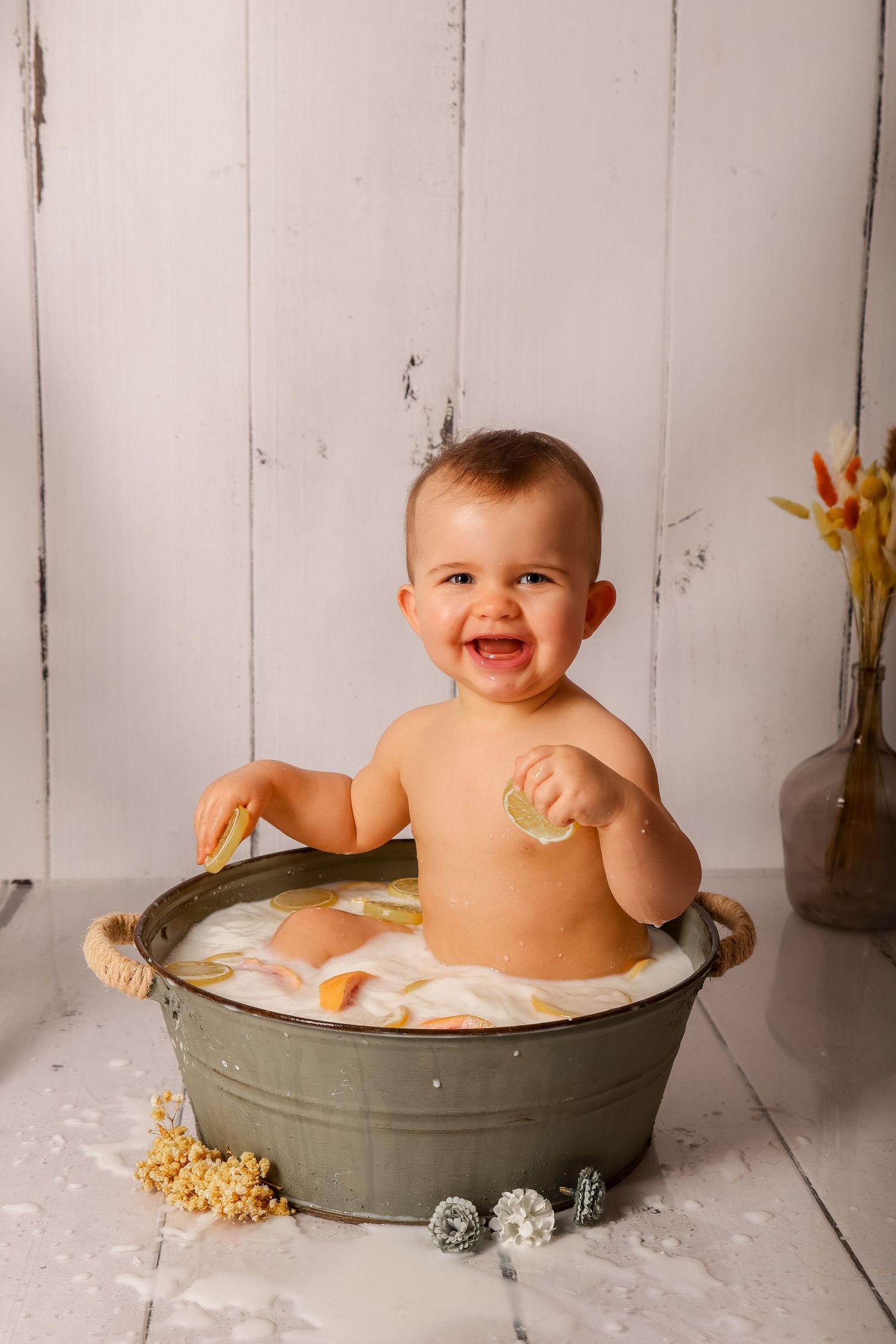Bébé souriant dans un bain de lait aux agrumes, séance photo enfant en studio par Cindy Poulet Photographe