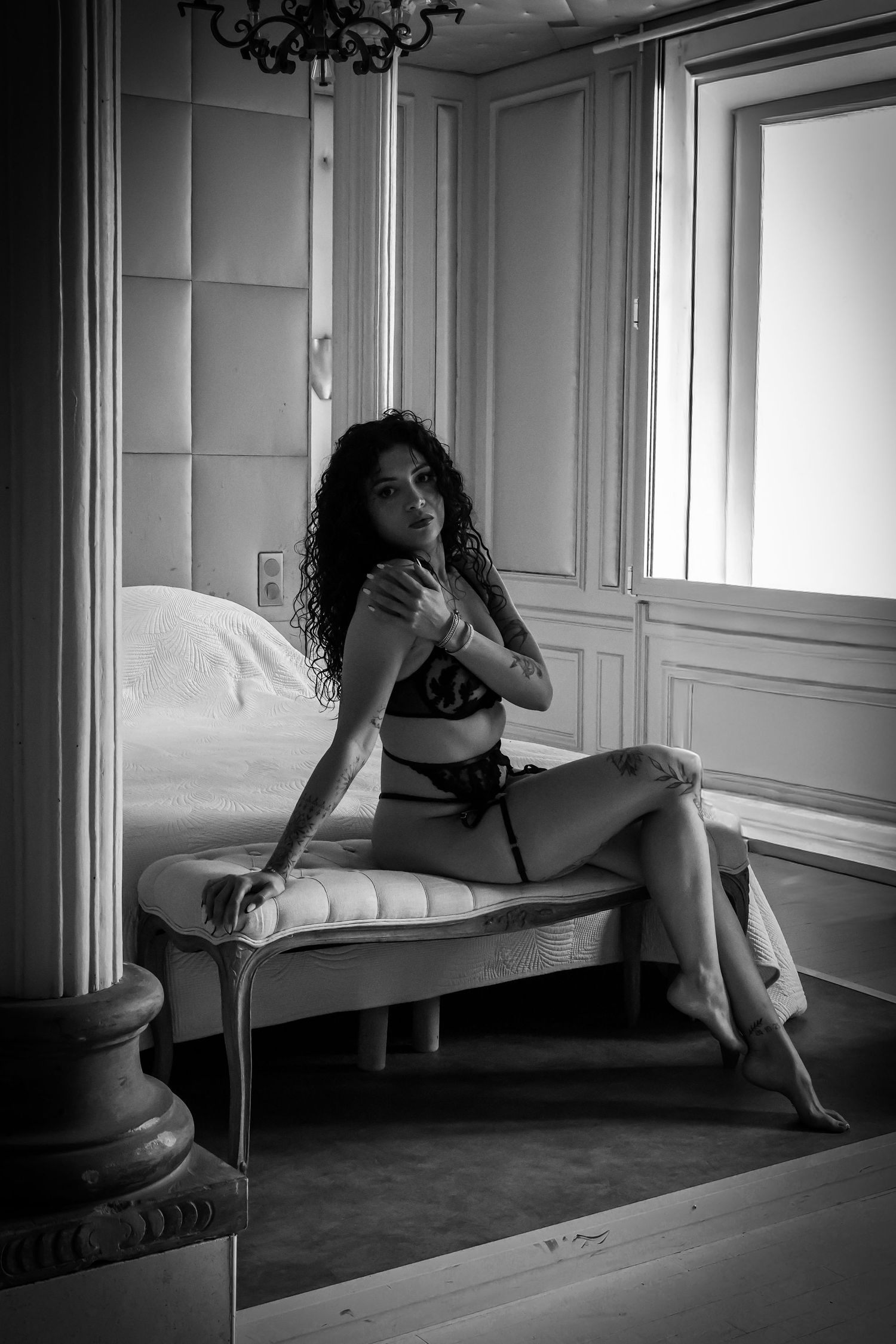 Femme en lingerie assise de manière sensuelle sur un banc blanc, boudoir
