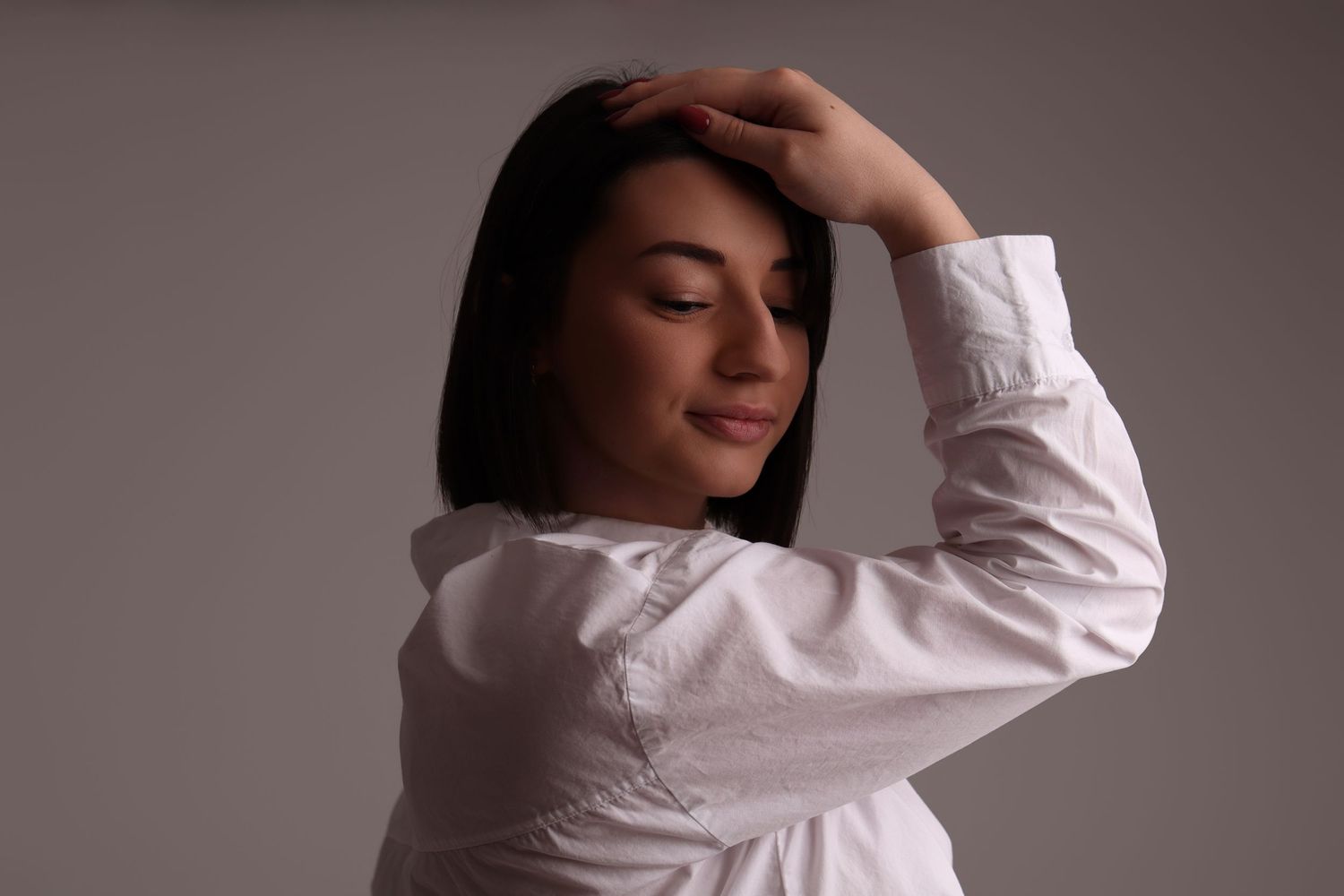 Femme en chemise blanche avec main sur la tête, portrait dynamique