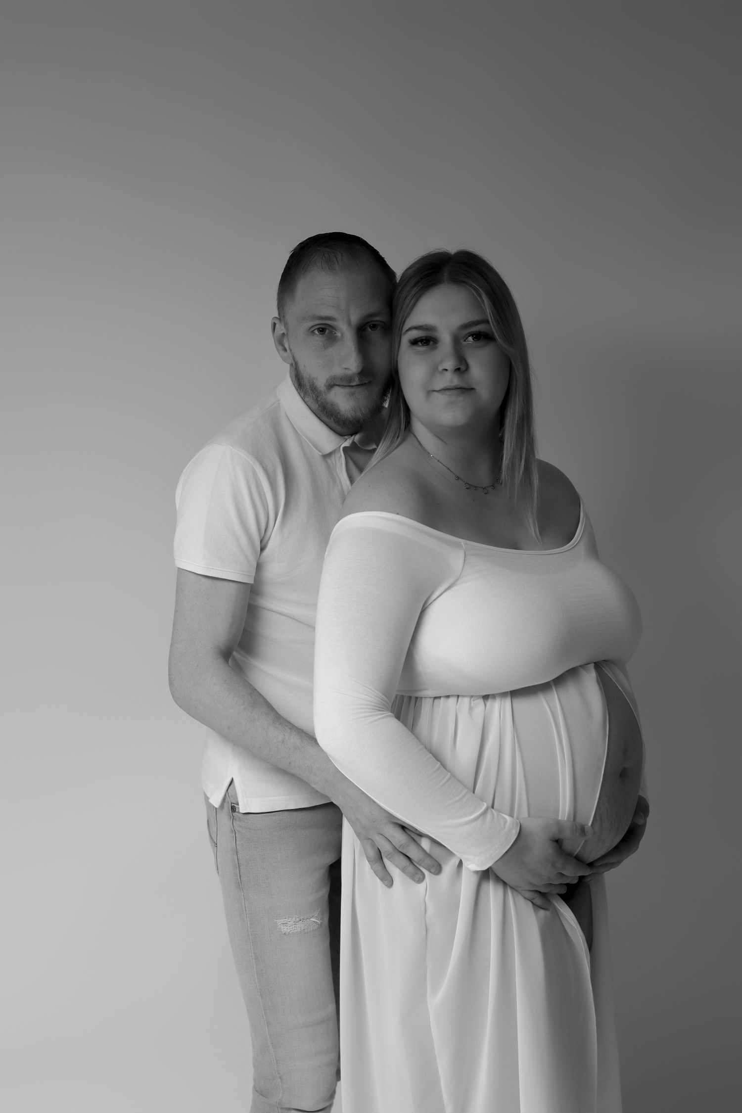 Couple en studio attendant un bébé, femme enceinte en blanc, photo grossesse